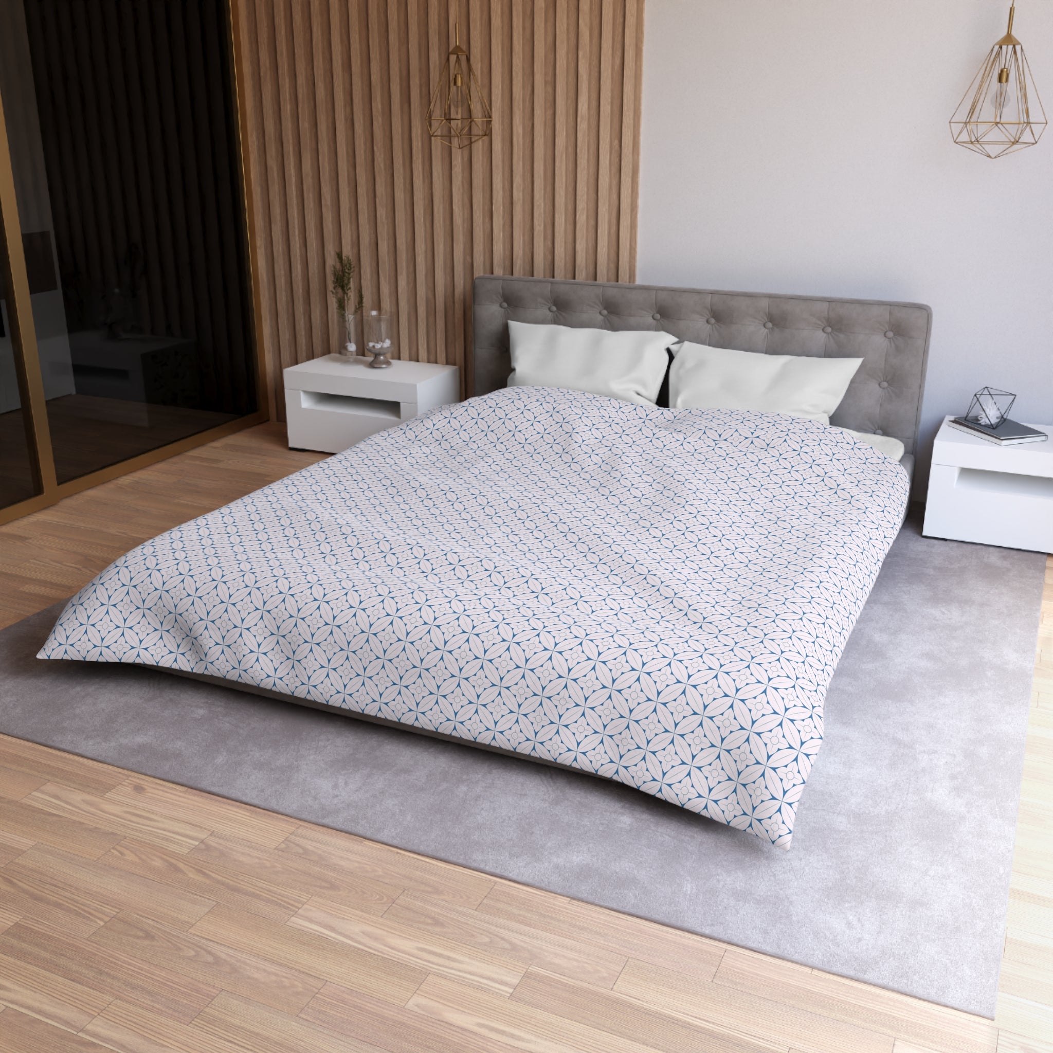 a modern bedroom with a large bed, a gray headboard, and a gray and white patterned comforter. The room has a wooden floor and white walls, creating a clean and minimalist aesthetic.