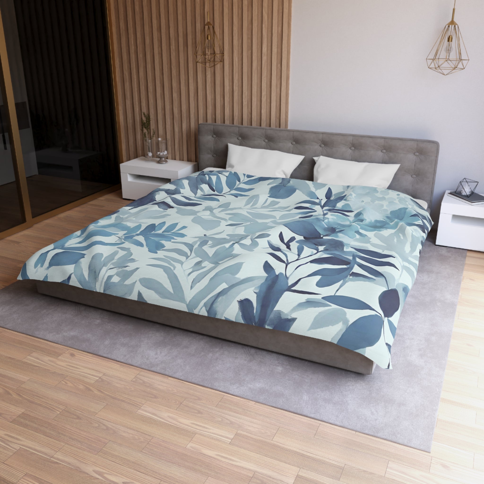 a modern bedroom with a large bed, a gray headboard, and a blue and white leaf-patterned comforter. The room has a wooden floor and white walls, creating a serene and tranquil atmosphere.