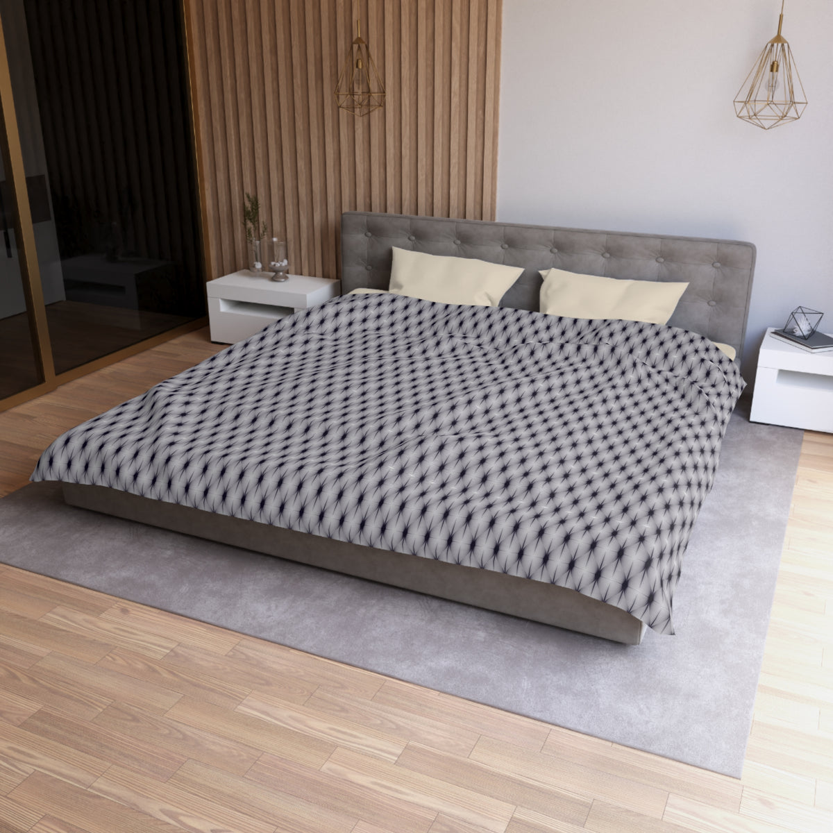 a modern bedroom with a large bed, a gray headboard, and a patterned comforter. The room has a wooden floor and white walls, creating a clean and minimalist aesthetic.