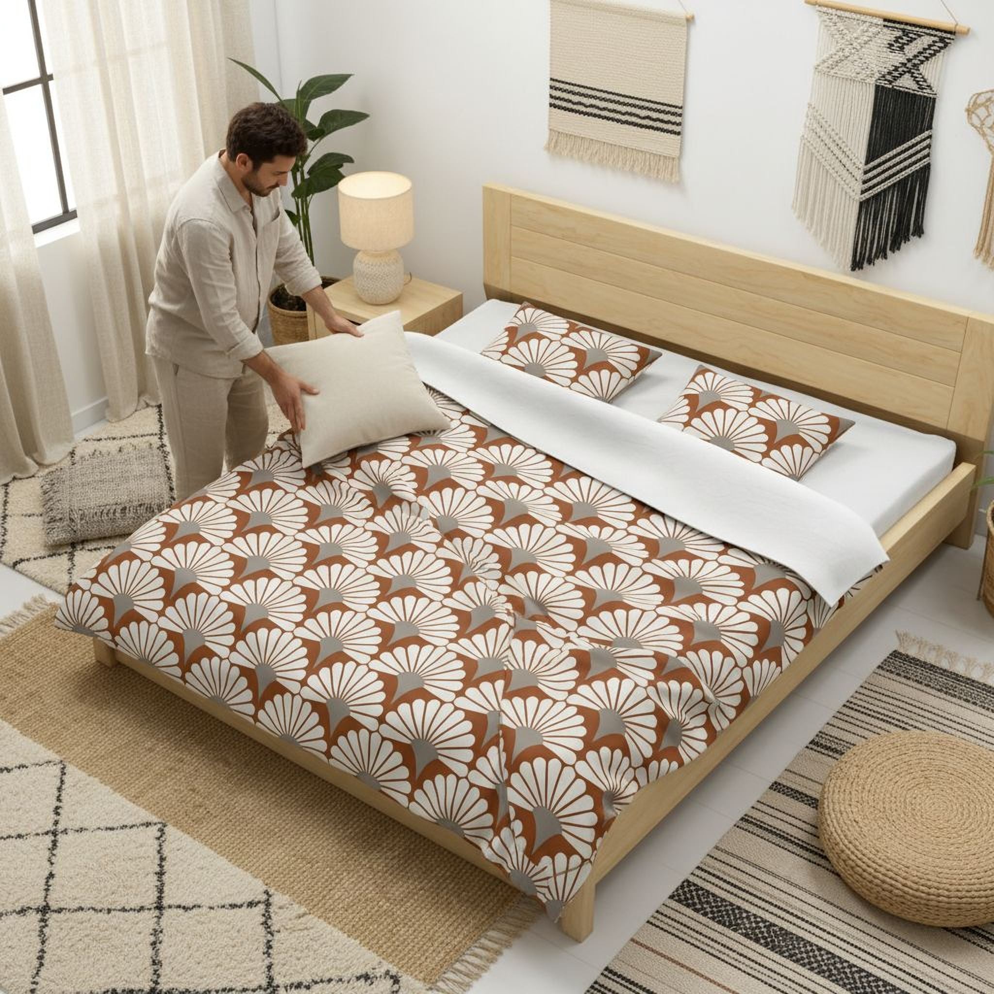 A man is arranging pillows on a bed with a floral print comforter and pillows in a bedroom setting.