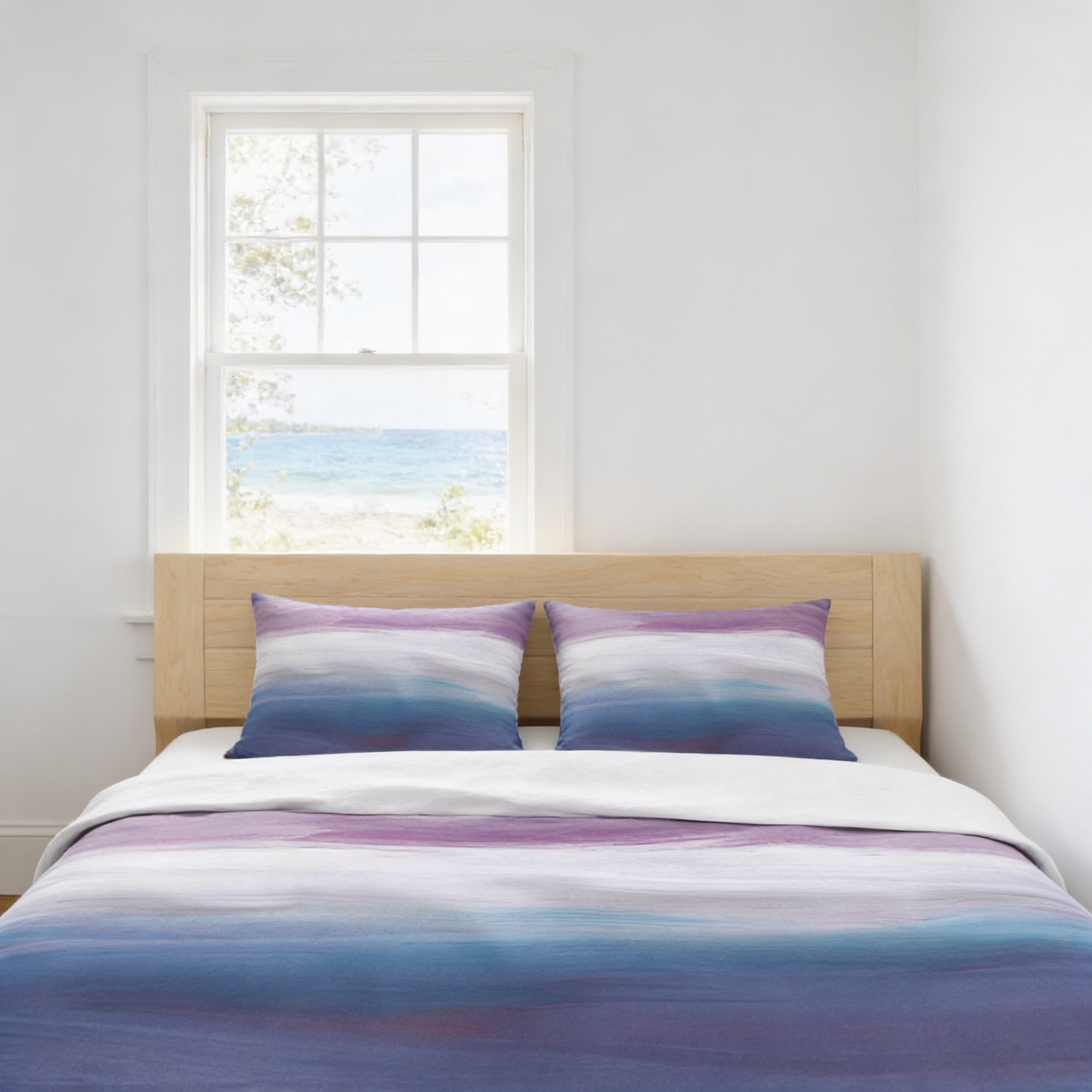a bedroom with a bed and a window overlooking a beach. The bed has a white and purple striped comforter and two matching pillows.