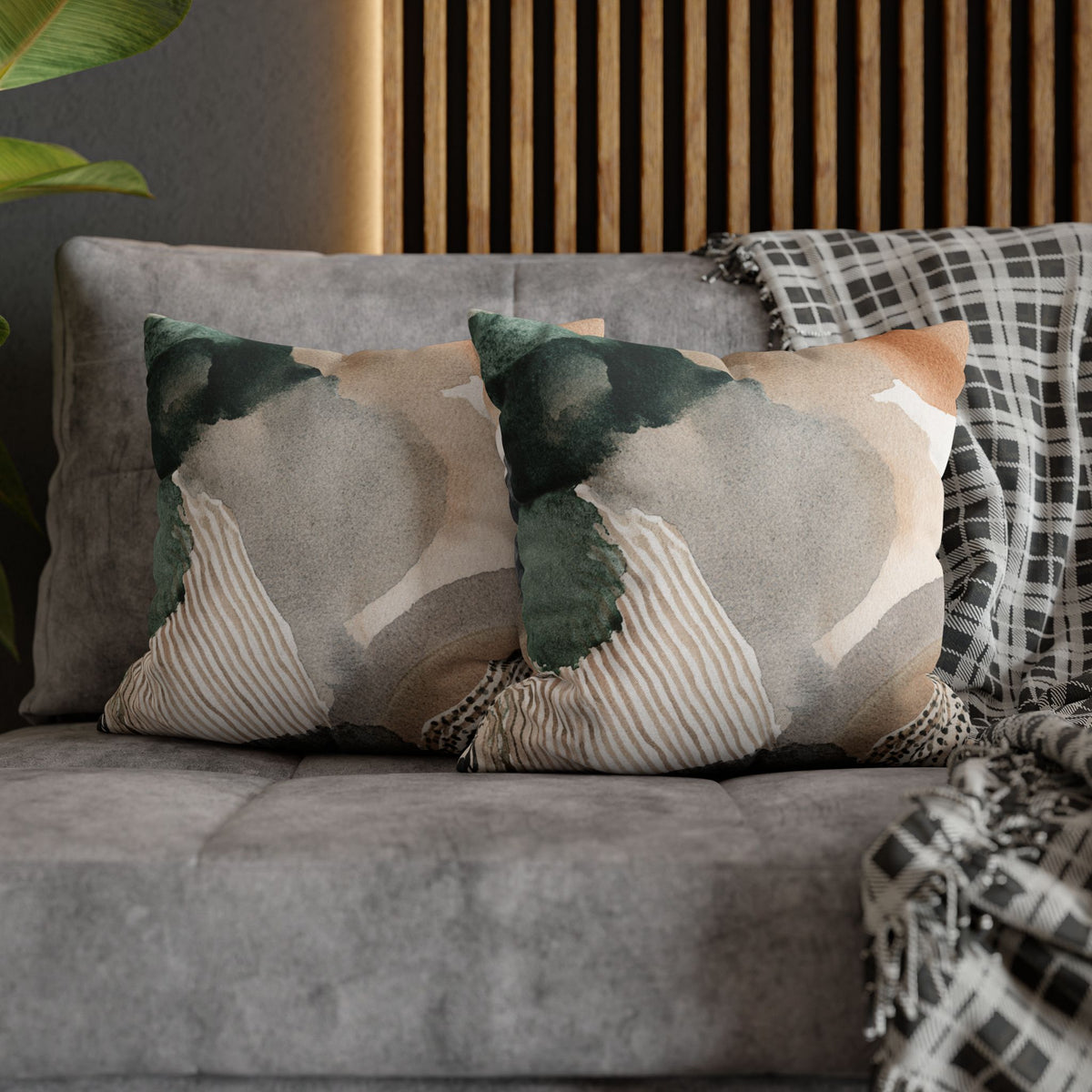 a gray couch with two decorative throw pillows on it. The pillows have a patterned design with a mix of green, brown, and white colors.