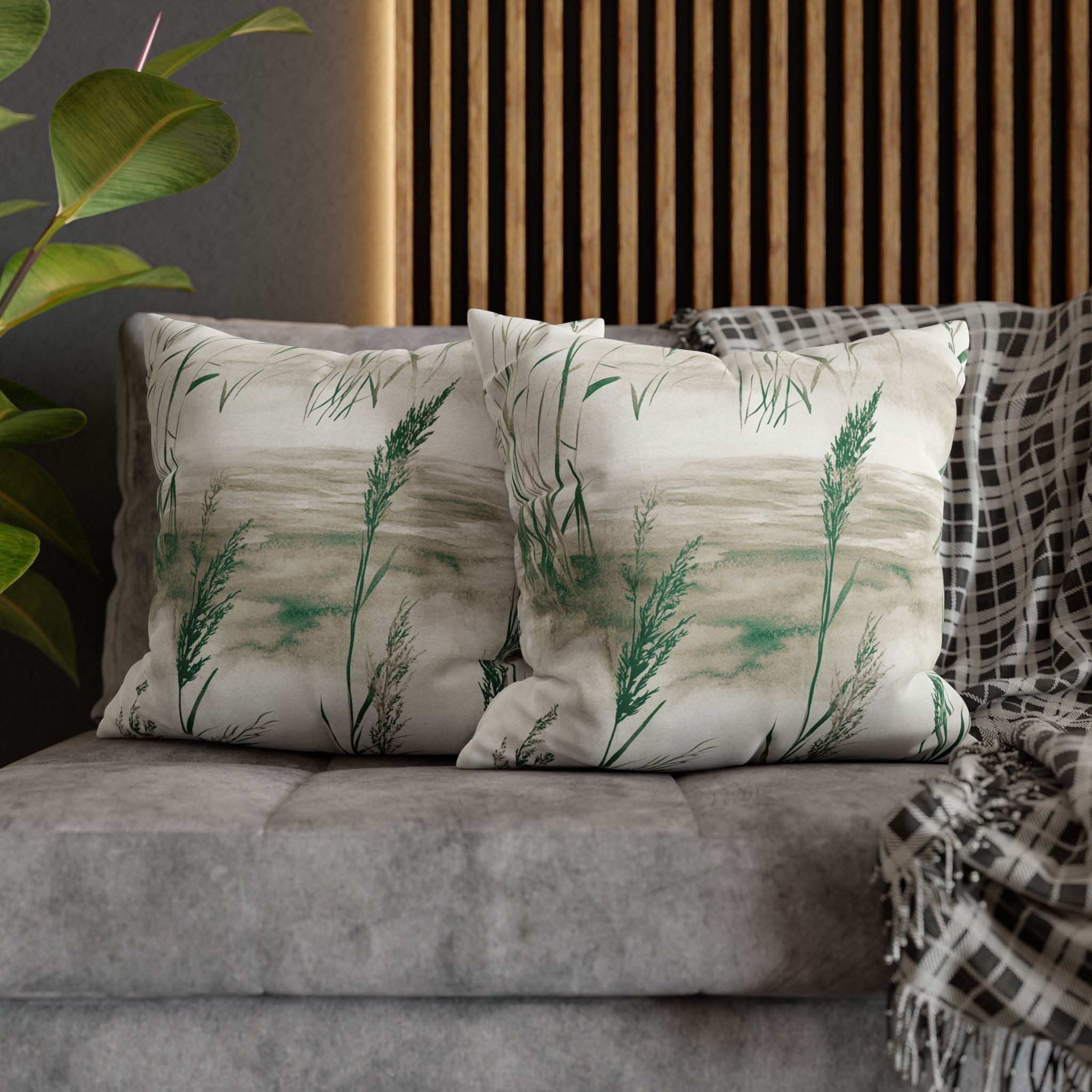 a gray couch with two matching throw pillows, each with a green plant design, placed on top of it.