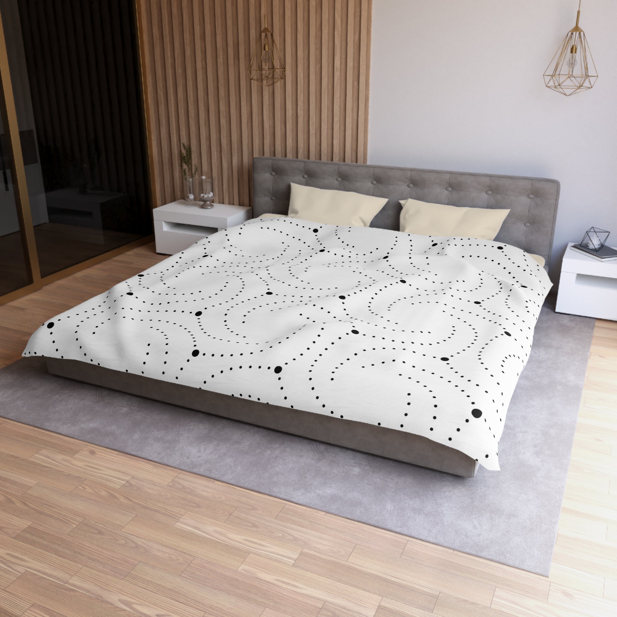 A modern bedroom with a gray tufted headboard, a white bedspread with black polka dots, and a wooden floor.