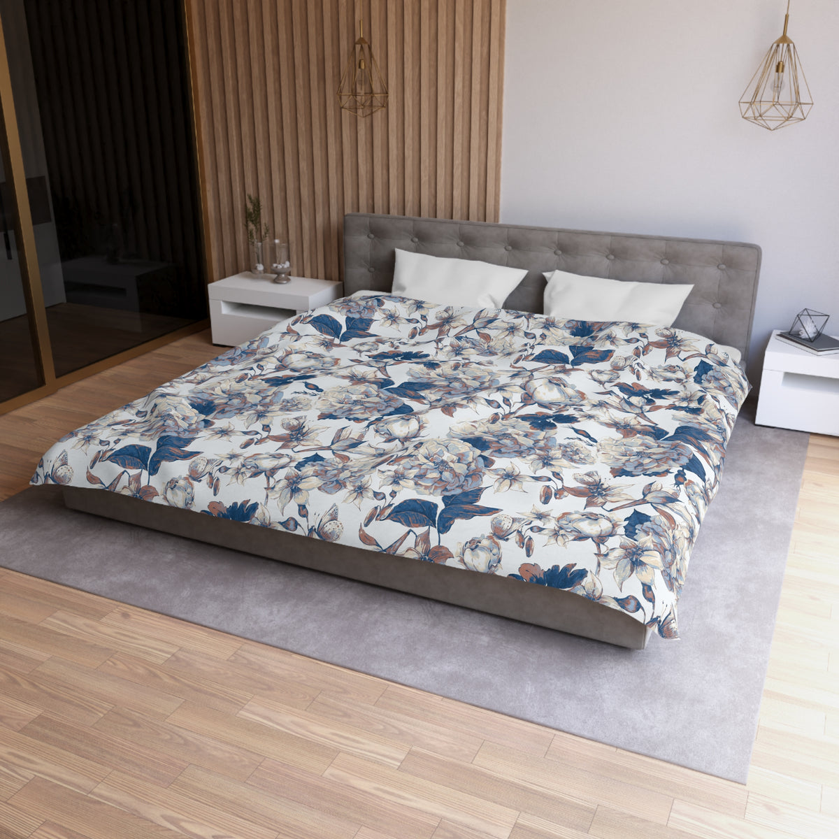a modern bedroom with a large bed, a gray headboard, and a floral patterned comforter. The room has a wooden floor and white walls, creating a serene and elegant atmosphere.