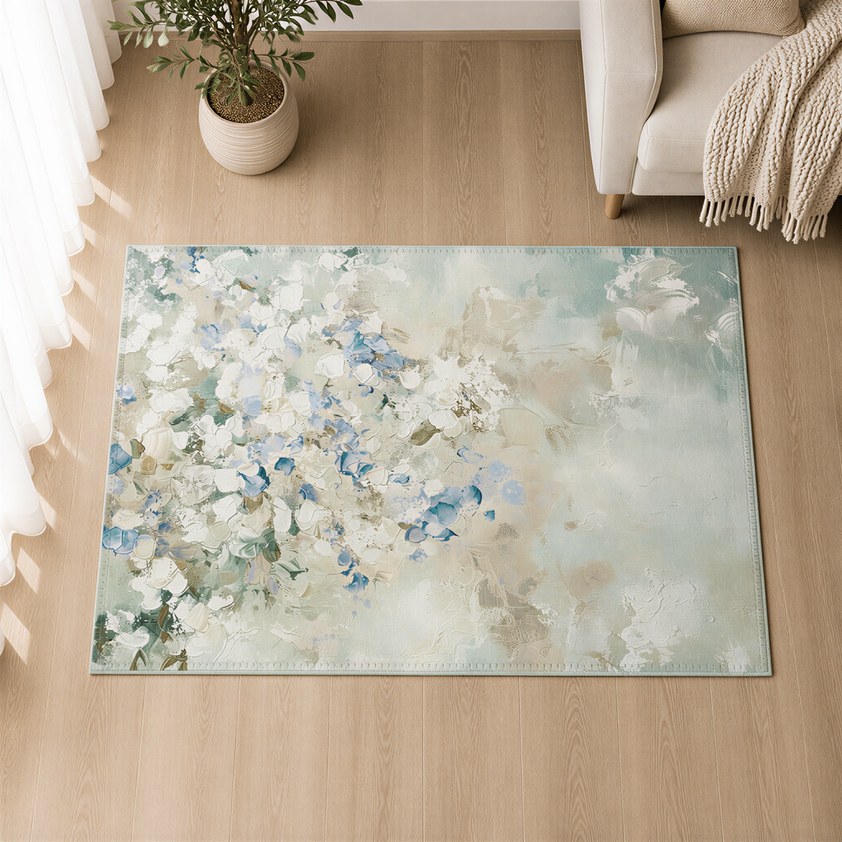 a large, rectangular rug with a floral design in shades of blue and white, placed on a wooden floor. The rug is positioned in front of a window, with a potted plant and a beige armchair visible in the background.