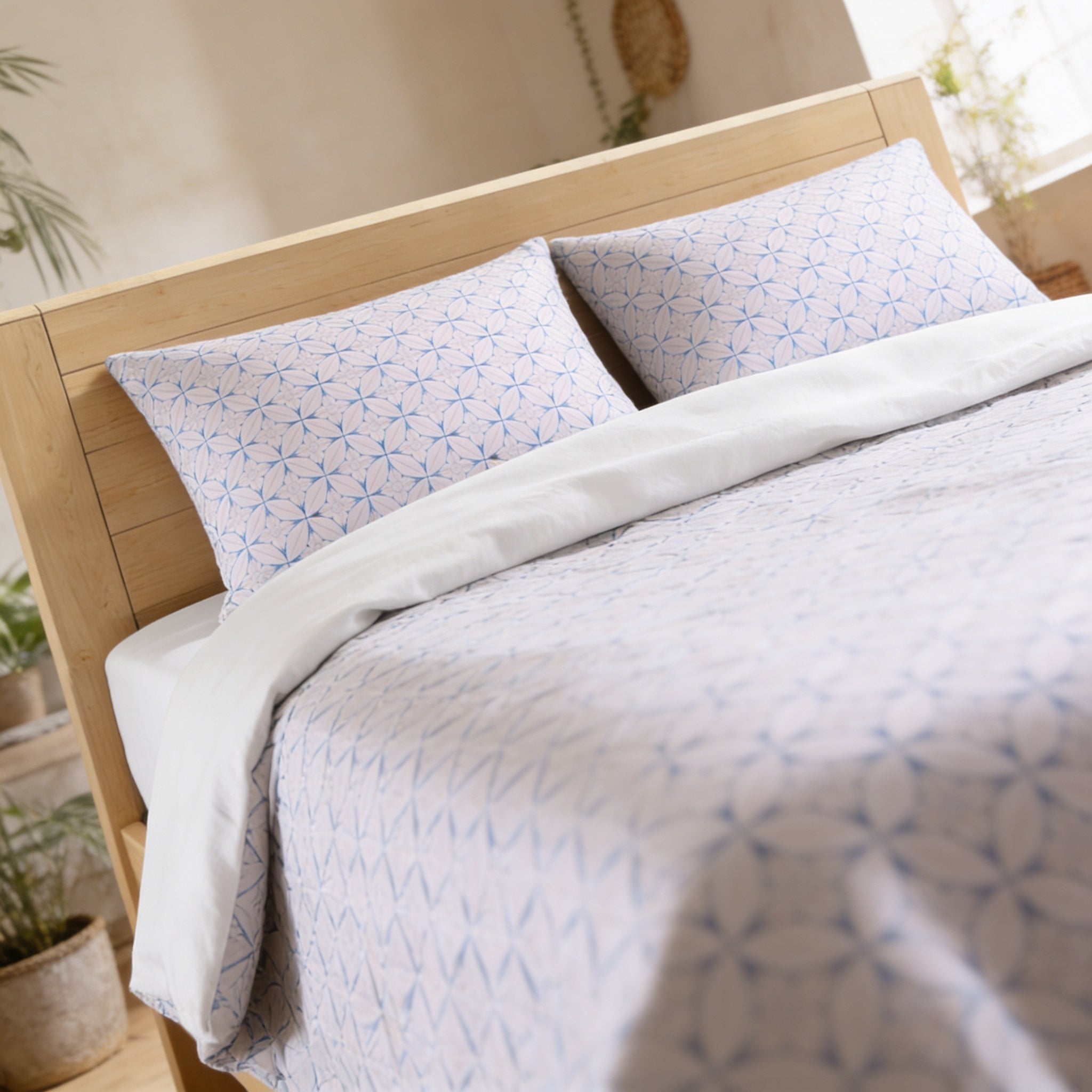 a neatly made bed with a white and blue patterned comforter and matching pillows.