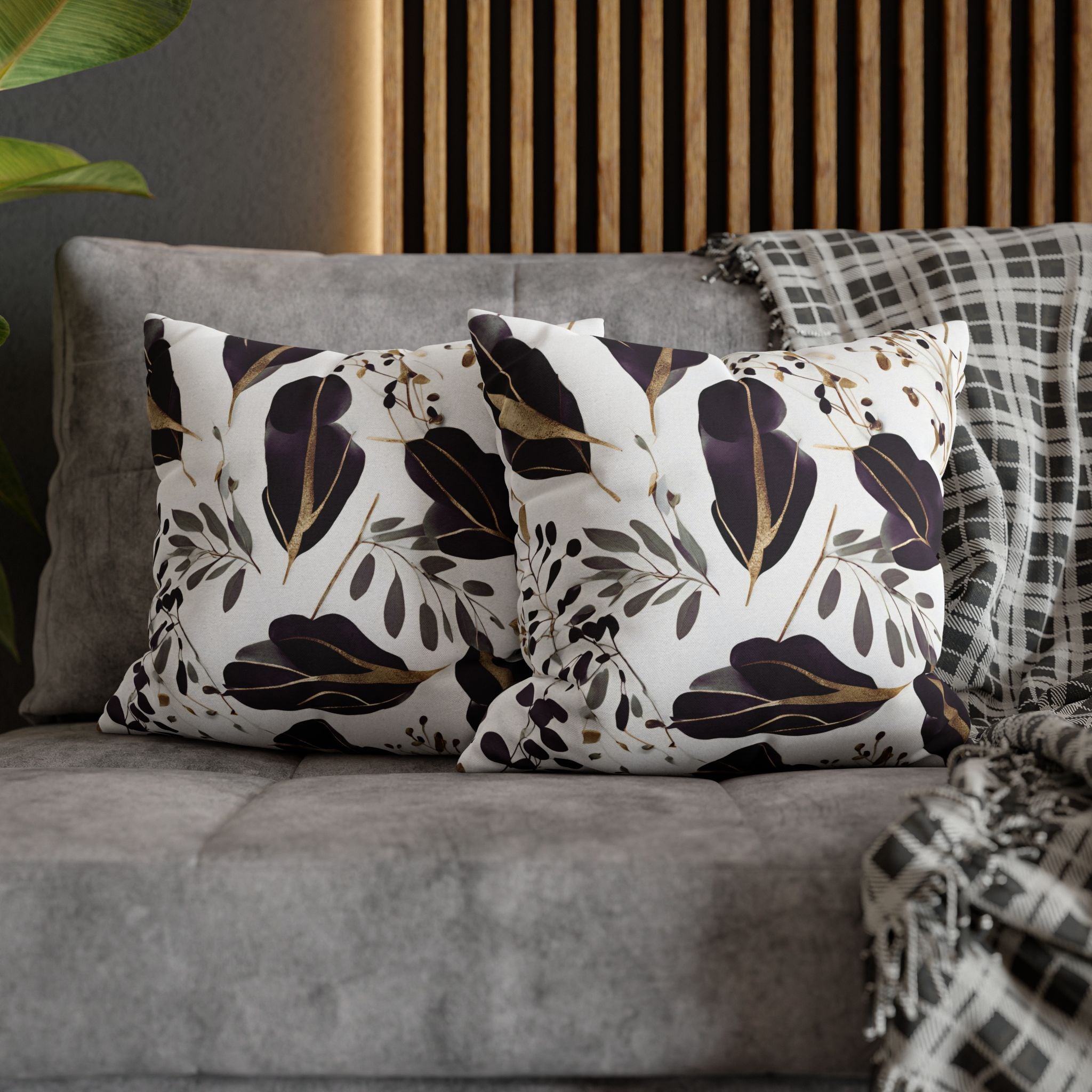 a gray couch with two decorative throw pillows featuring a floral pattern in shades of black and white.