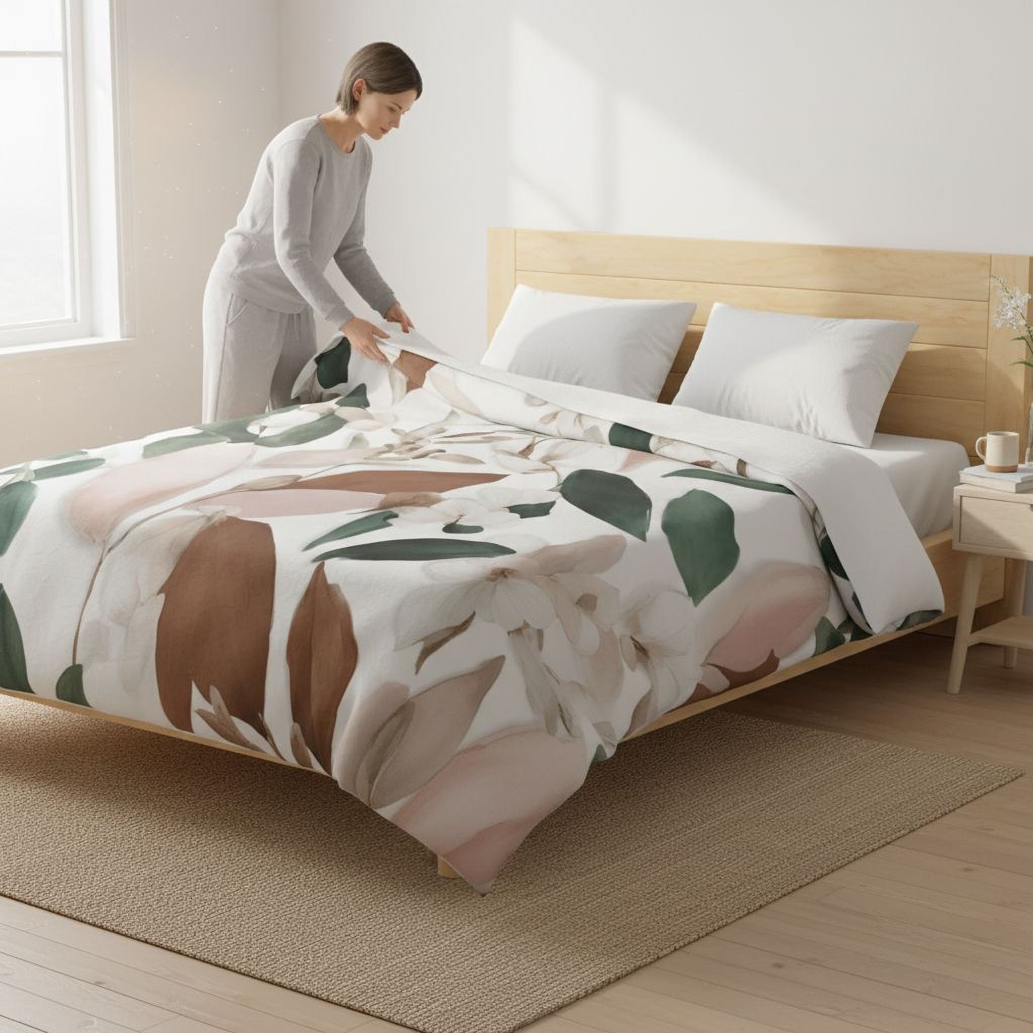 A woman is arranging a floral print bedding set on a bed with a wooden headboard.