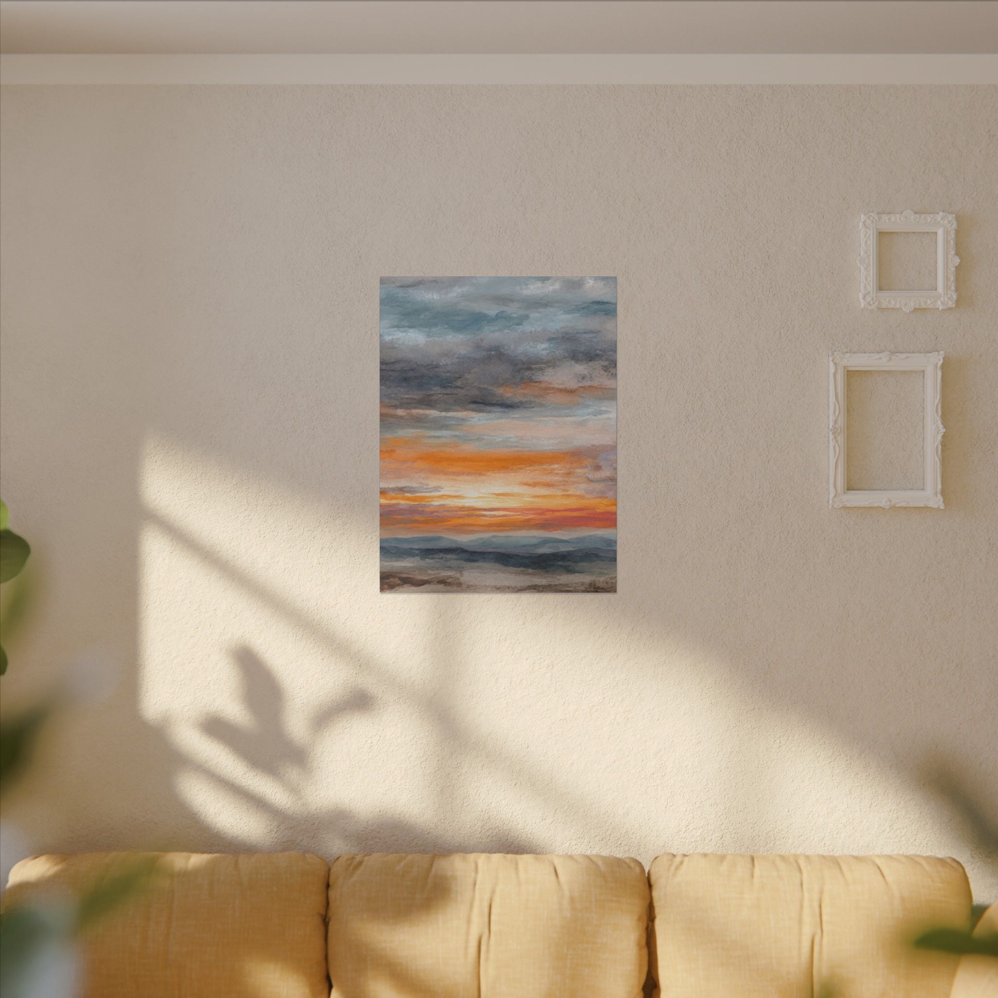 a cozy living room with a beige sofa and a framed painting of a sunset on the wall.