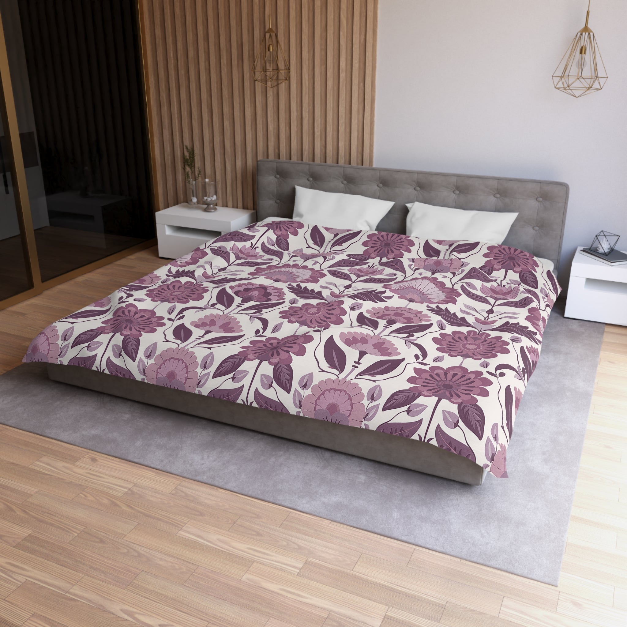 a modern bedroom with a large bed covered in a floral comforter and pillows. The bed is positioned against a wall with a wooden panel. The room has a wooden floor and a gray area rug. There are two nightstands on either side of the bed, and a pendant light hangs above the bed.