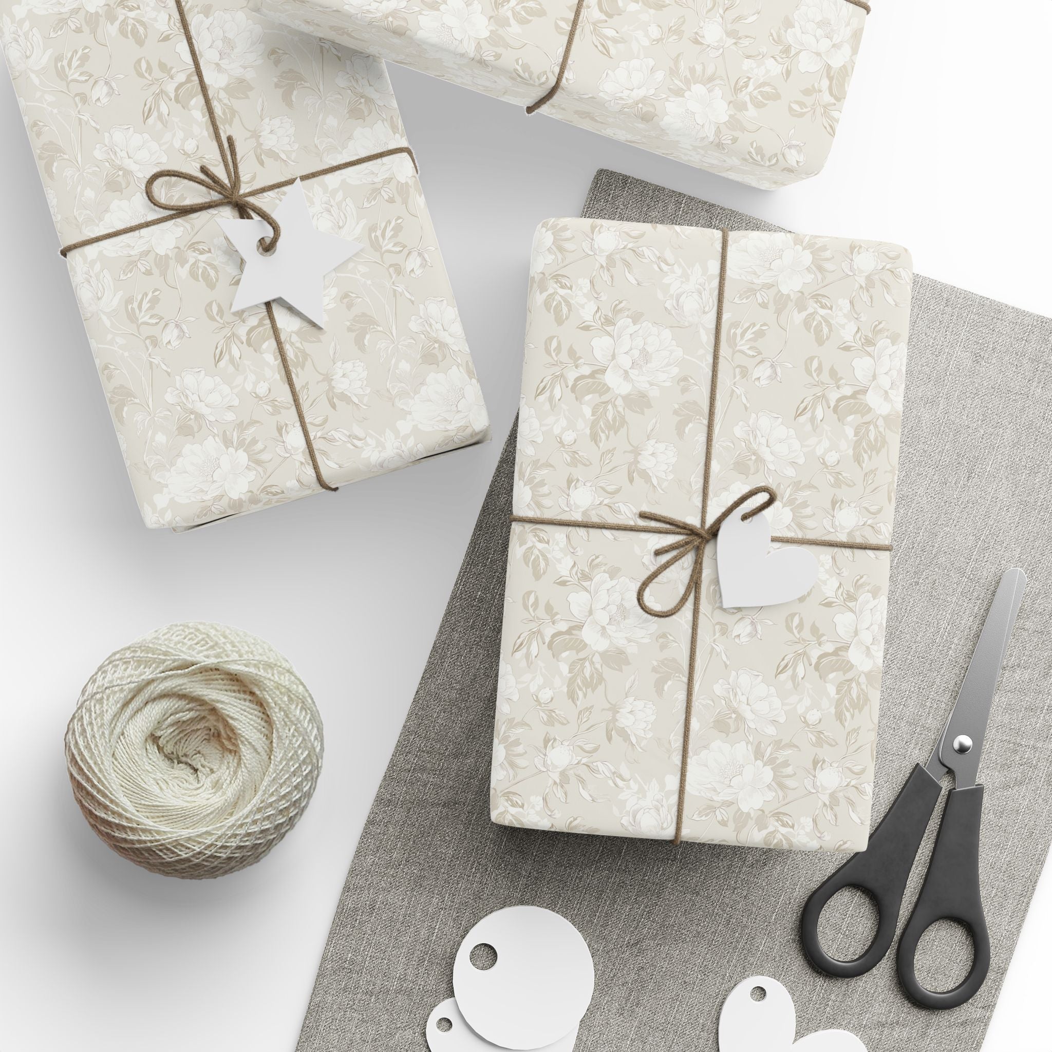 a collection of gift-wrapped presents, a spool of thread, a pair of scissors, and some tags, all arranged on a gray surface.