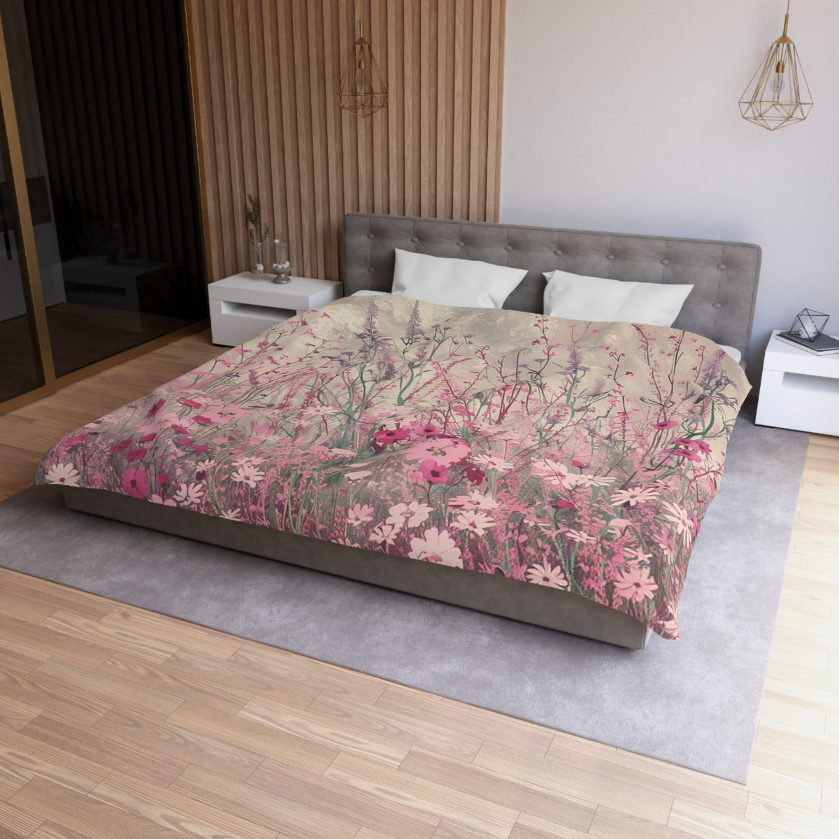 a bedroom with a large bed covered in a floral print comforter. The bed is positioned against a wall with a wooden panel. The room has a wooden floor and a white nightstand on the left side of the bed. There is also a pendant light hanging above the bed.