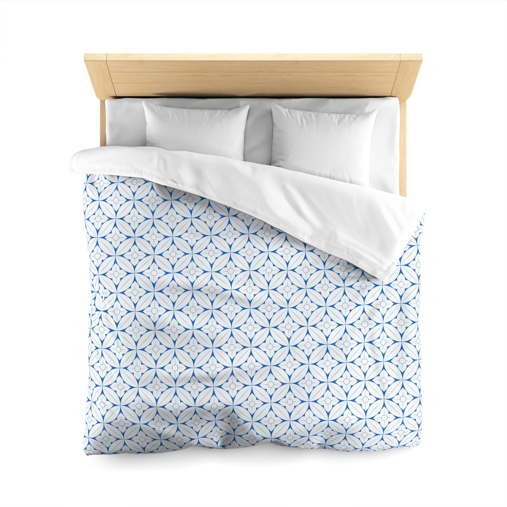 a neatly made bed with a blue and white patterned comforter and pillows.