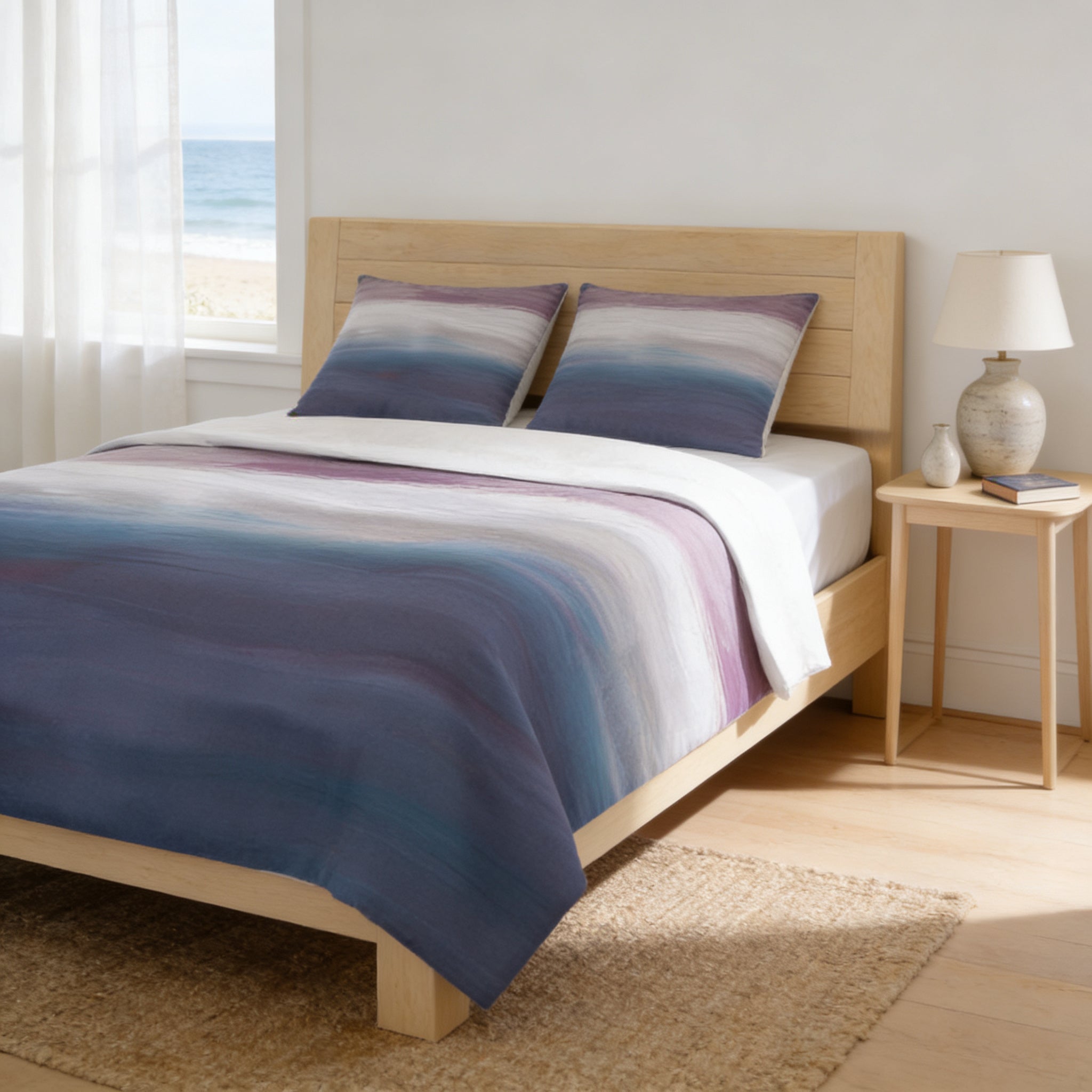 a serene bedroom scene with a bed featuring a blue and purple striped comforter and matching pillows, a wooden headboard, and a nightstand with a lamp. The room has a window overlooking the ocean, creating a peaceful and relaxing atmosphere.