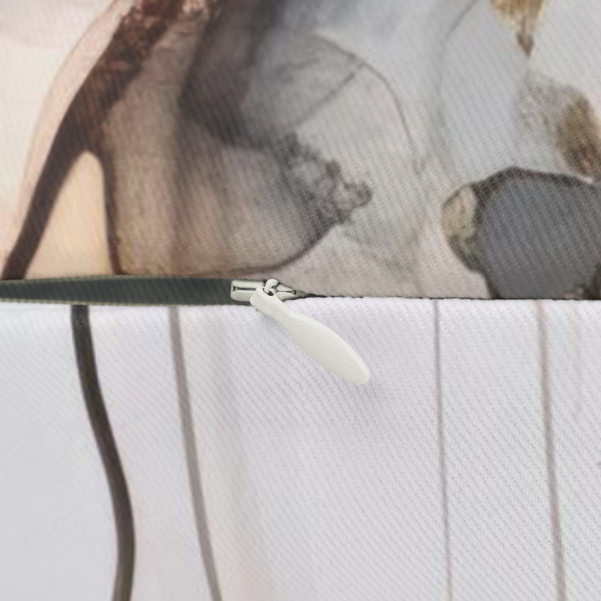 a close-up view of a zipper on a fabric, with a blurred background that appears to be a patterned fabric or a similar material.