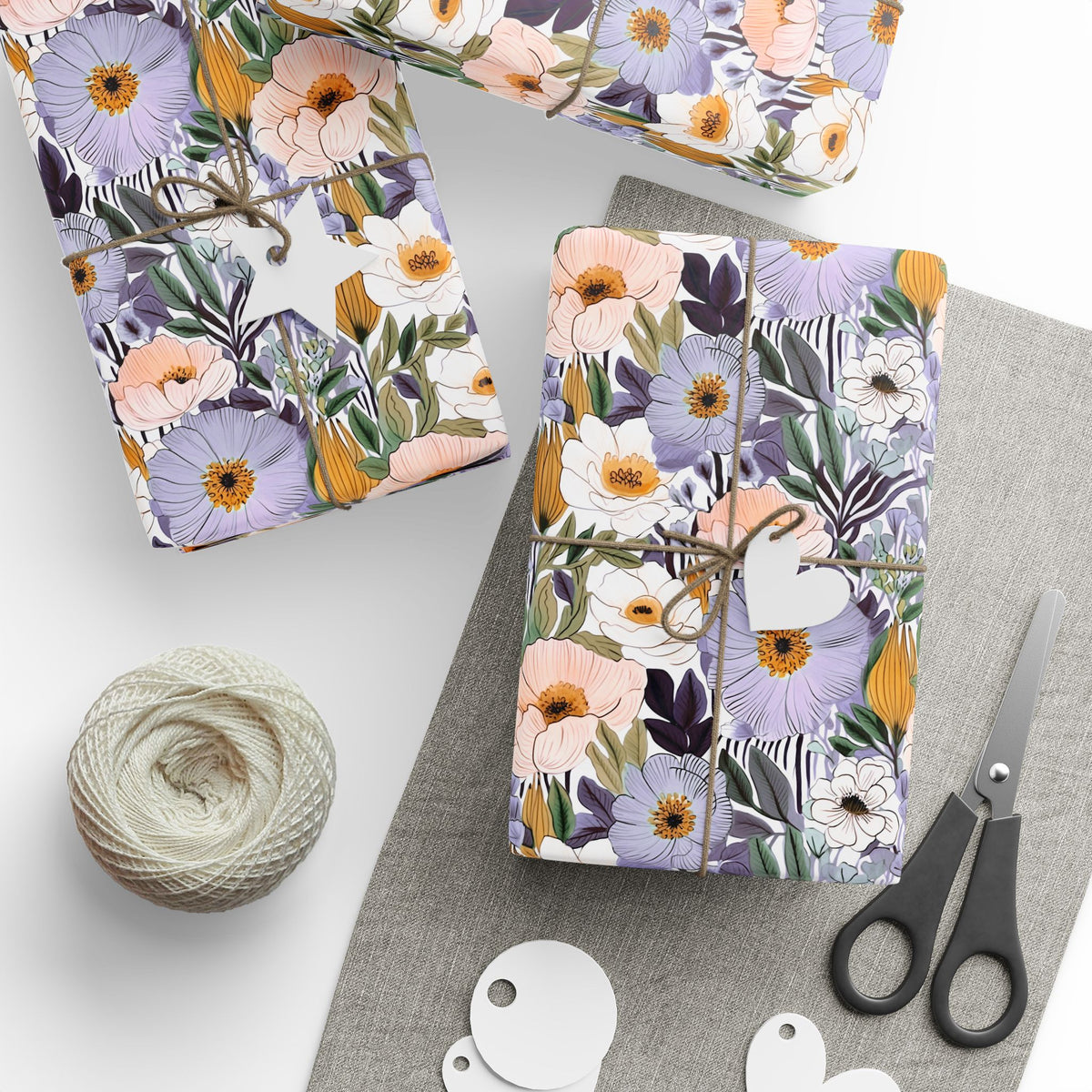 Lilac and peach garden blossom wrapping paper on gifts tied with twine, with gift tags and scissors