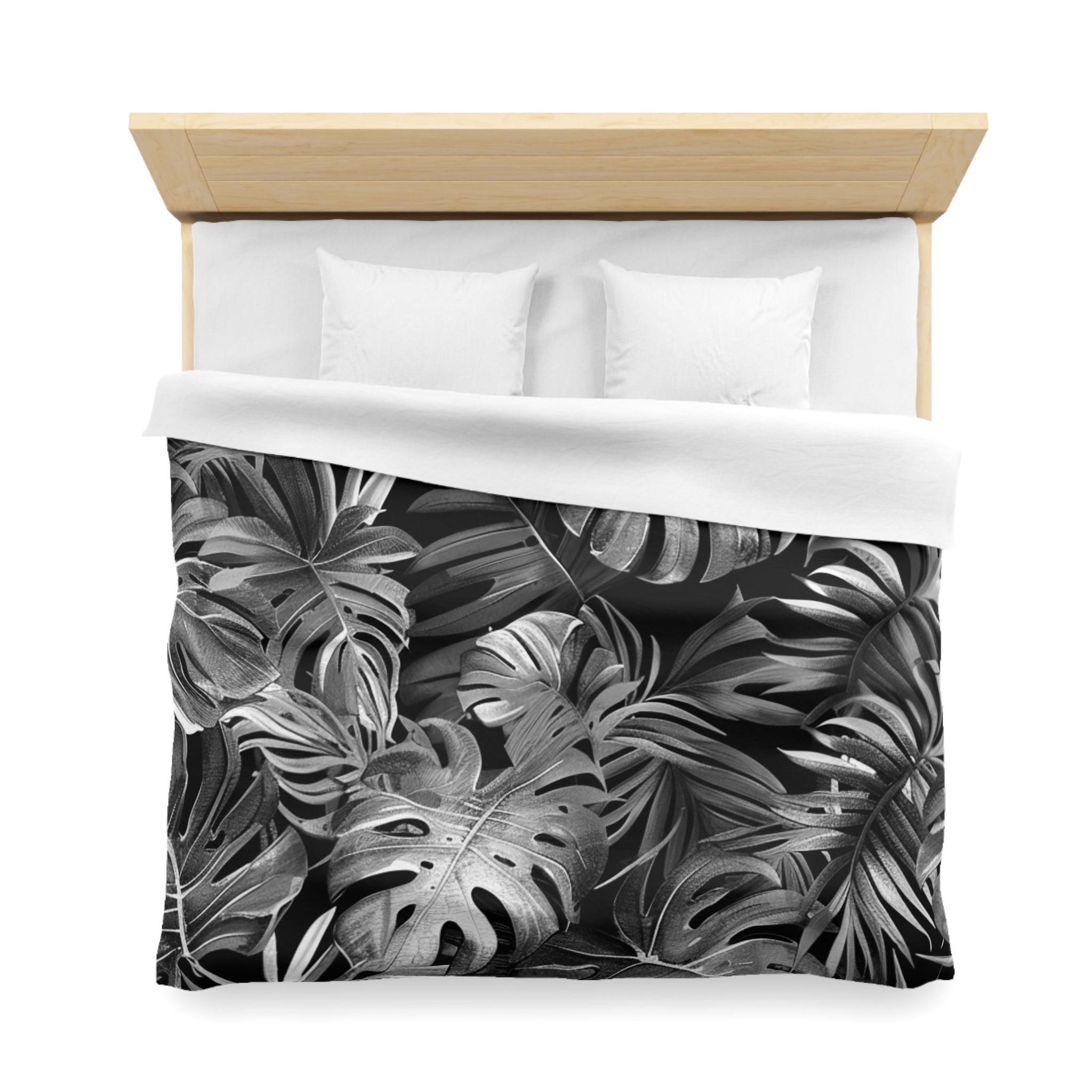 a bed with a black and white tropical leaf pattern on the duvet cover.