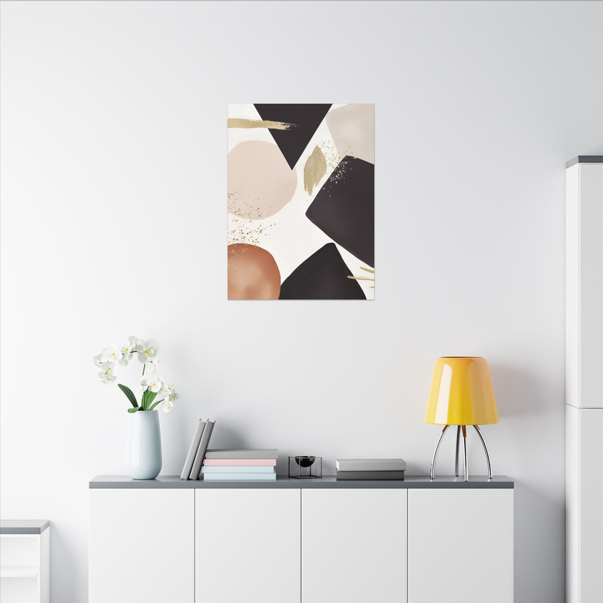 a minimalist living space with a white wall, a white cabinet, a yellow lamp, a vase with white flowers, and a framed abstract art piece hanging above the cabinet.