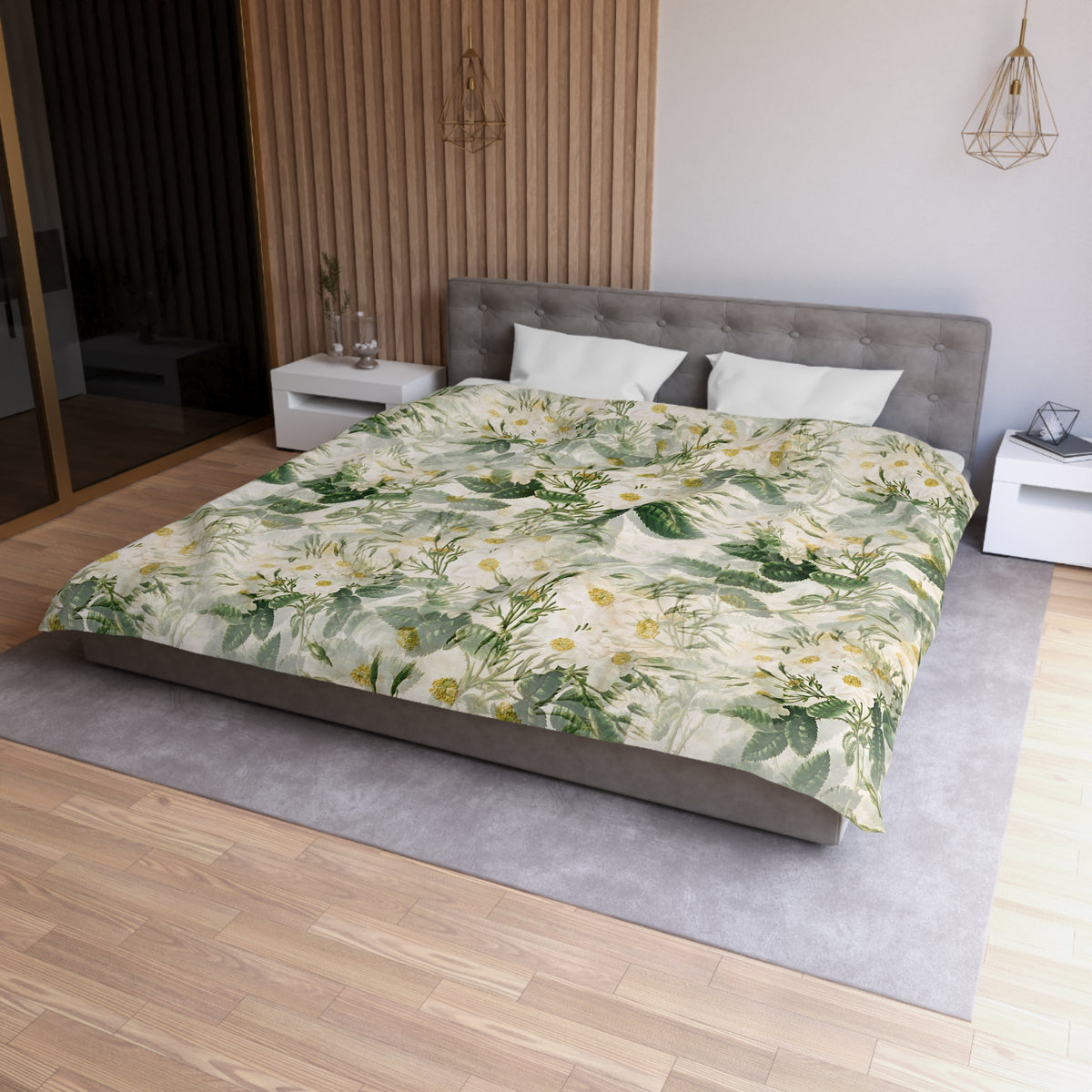 a modern bedroom with a large bed covered in a floral print comforter. The bed is positioned against a wall with a wooden panel. The room has a minimalist design, with a gray headboard and white nightstands. There is a pendant light hanging above the bed, and a vase on one of the nightstands. The overall color scheme of the room is neutral, with the floral print adding a touch of nature and color.