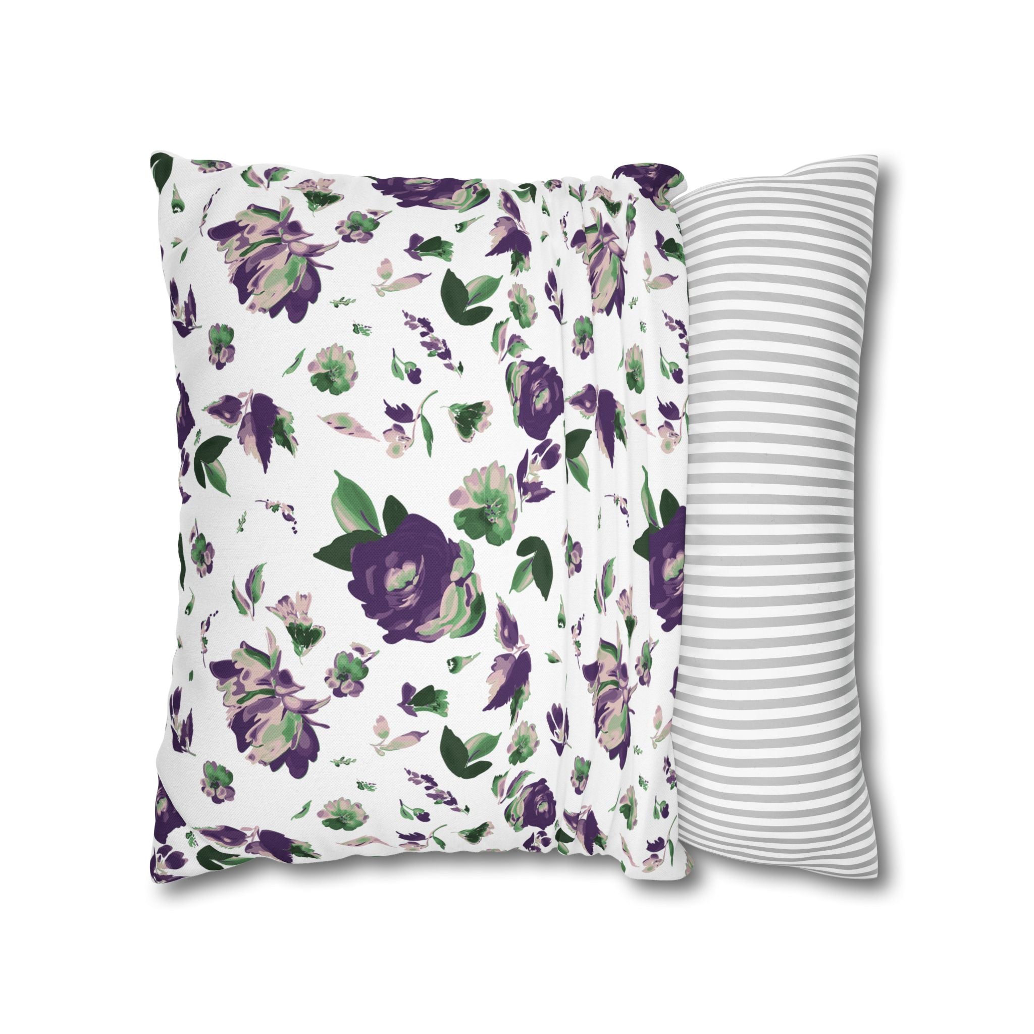 a white pillow with a floral print of purple and green flowers, and a gray and white striped pillow placed next to it.