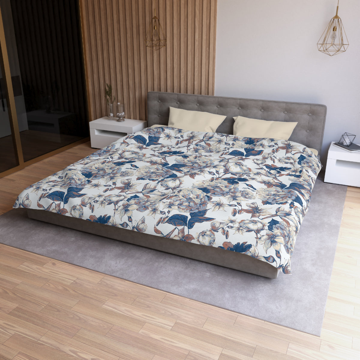 a modern bedroom with a large bed, a gray headboard, and a floral patterned comforter. The room has a wooden floor and white walls, creating a serene and elegant atmosphere.