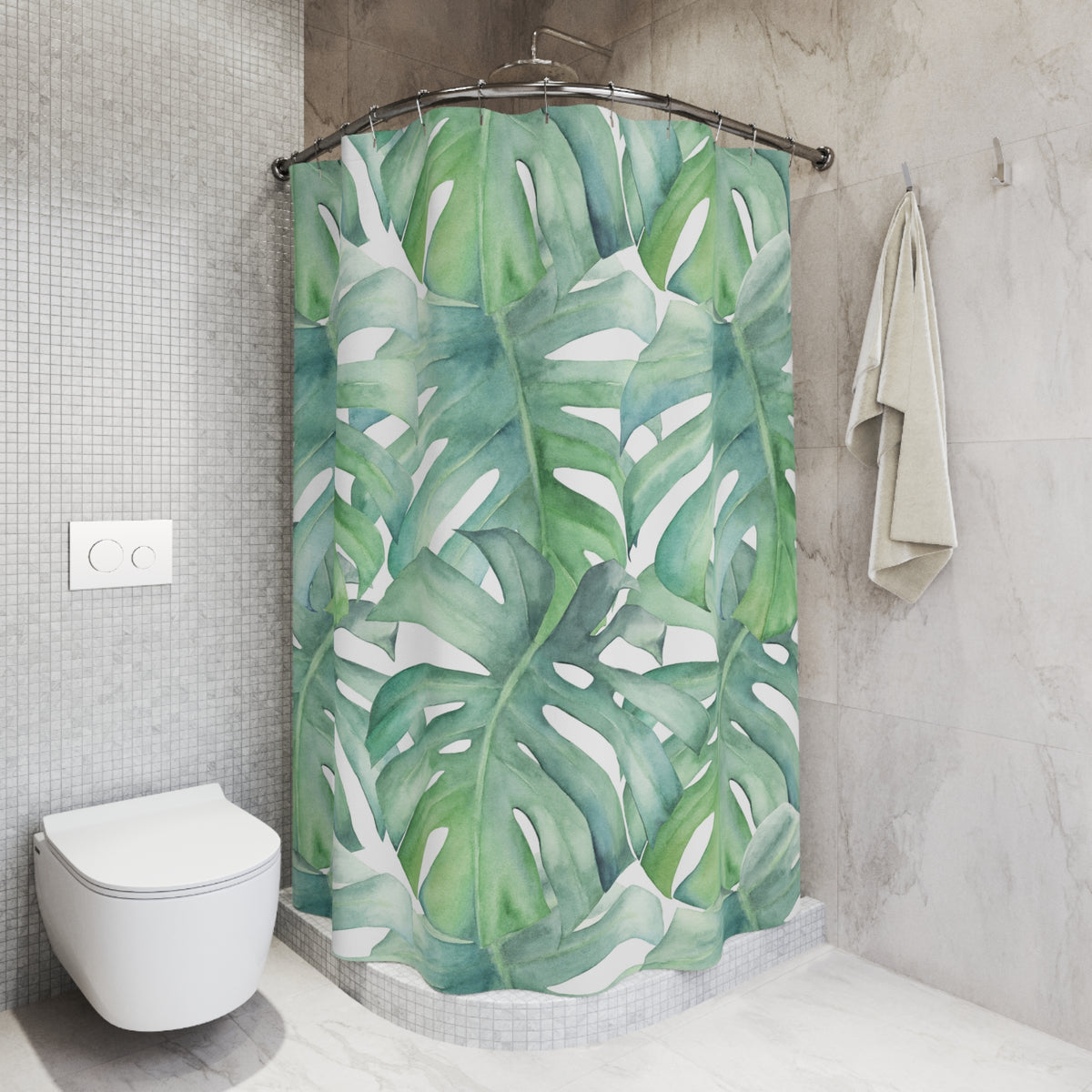 a bathroom with a shower curtain adorned with a tropical leaf pattern in shades of green and white. The shower curtain is hanging from a rod, and there is a towel hanging on the wall next to it. The bathroom has a white toilet and a tiled wall, creating a clean and modern aesthetic.