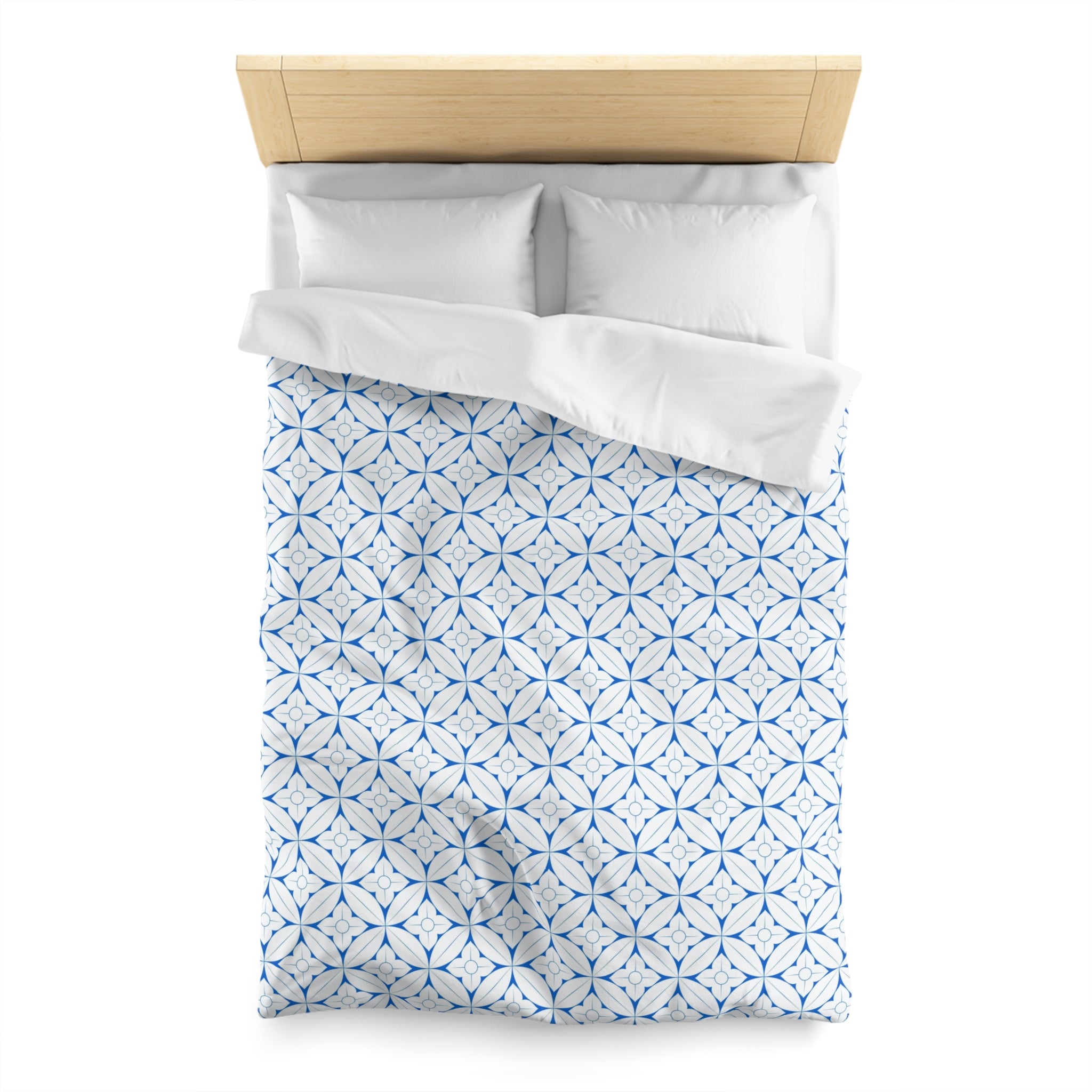 a neatly made bed with a blue and white patterned comforter and two white pillows.