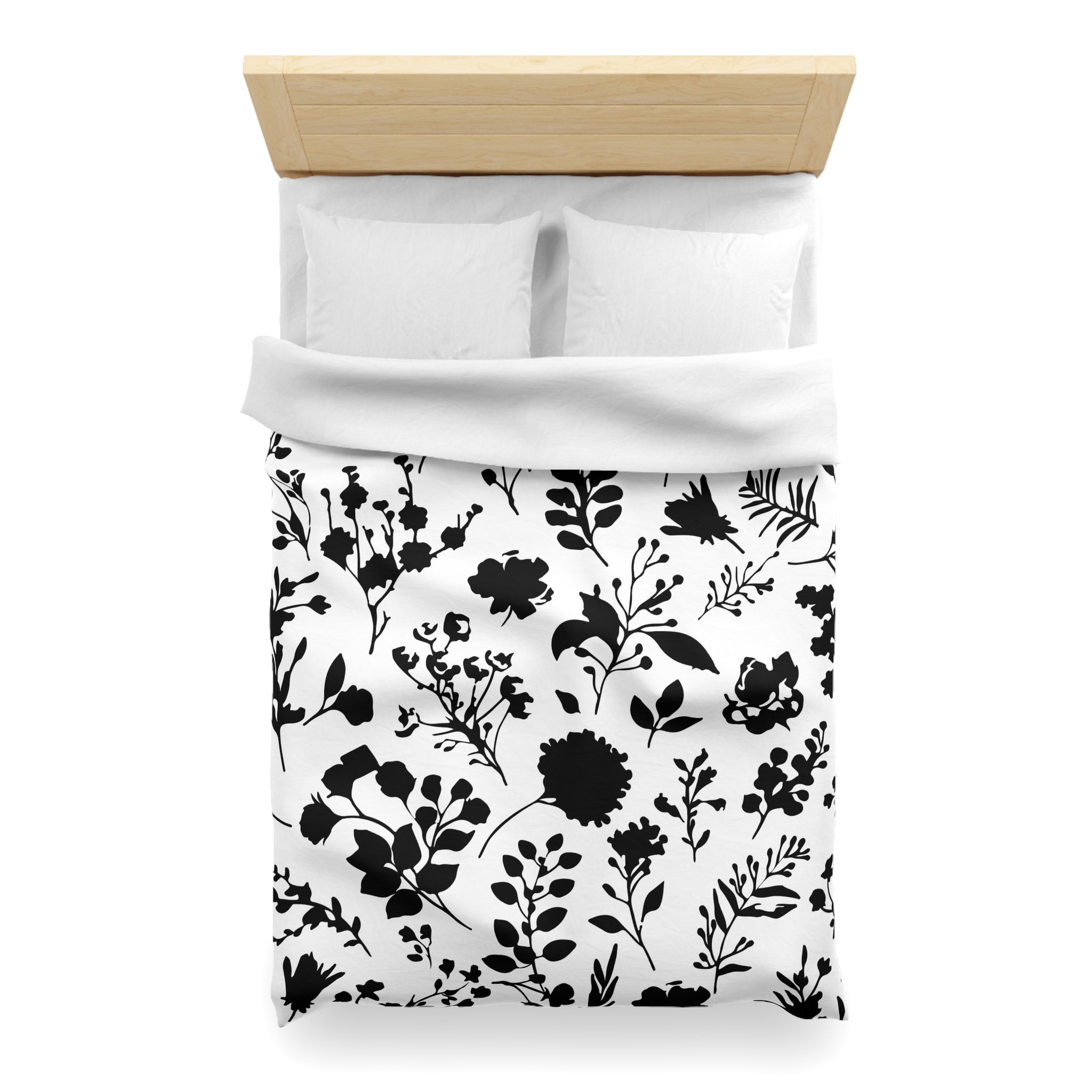 a neatly made bed with a black and white floral patterned comforter and pillows.
