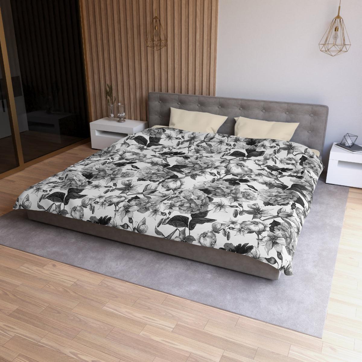 a modern bedroom with a large bed, a gray headboard, and a floral print comforter. The room has a wooden floor and white walls, creating a serene and elegant atmosphere.