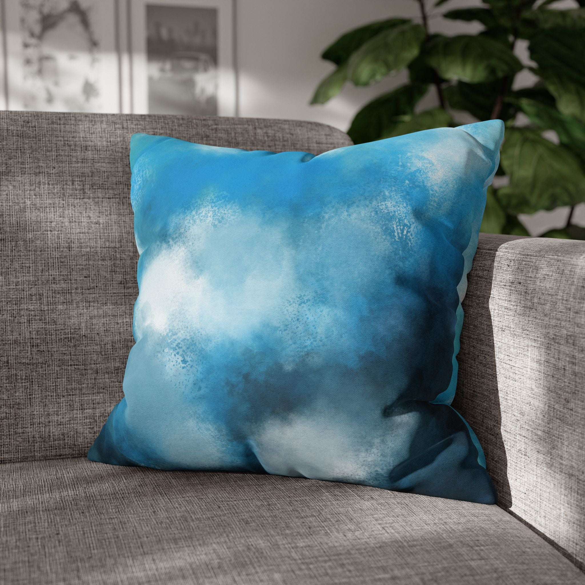 A gray couch with a blue and white abstract pillow resting on it.