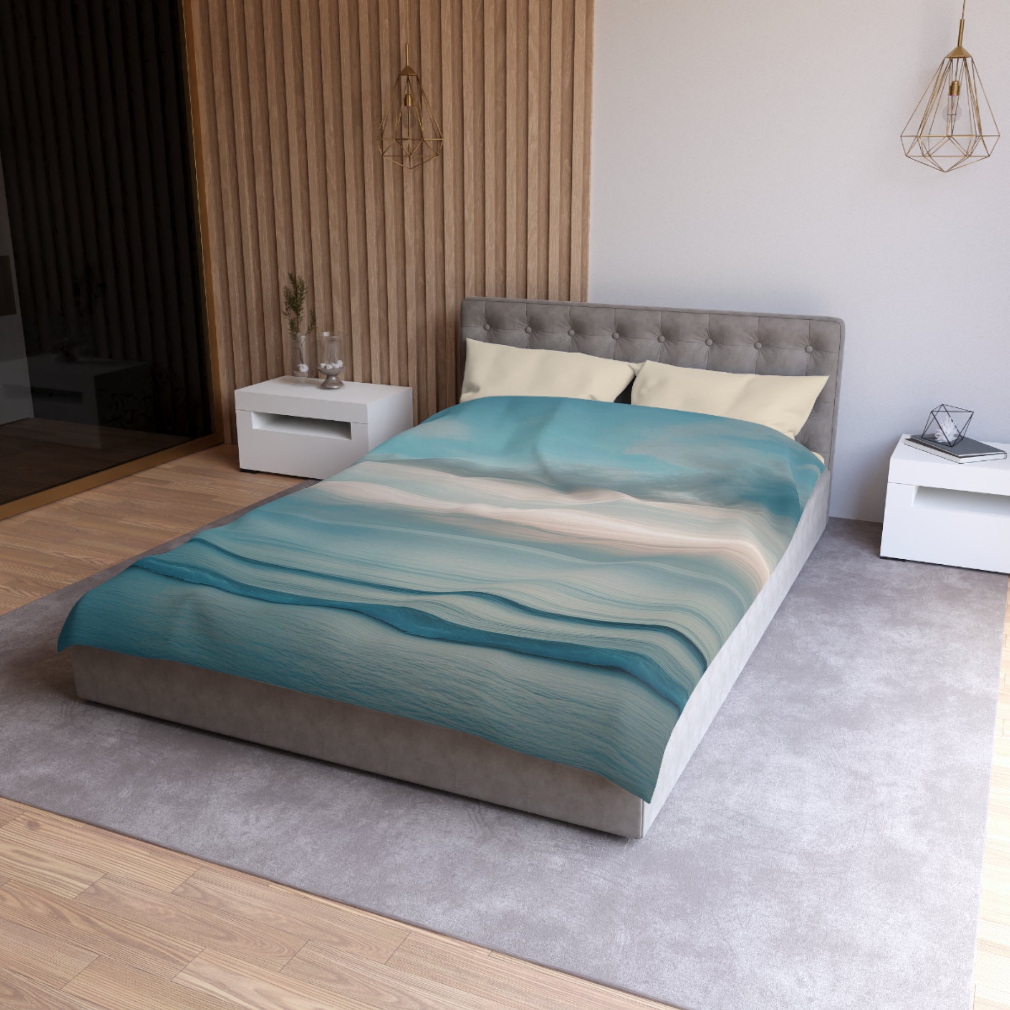 a modern bedroom with a large bed, a gray headboard, and a blue and white patterned comforter. The room has a neutral color scheme with white walls and a gray carpet. There are two nightstands on either side of the bed, and a pendant light hangs above the bed.