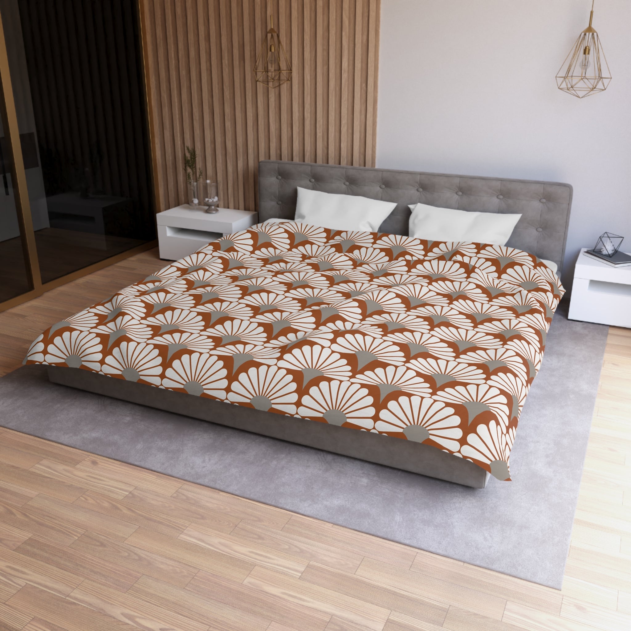 a modern bedroom with a large bed, a gray headboard, and a patterned comforter. The room has a wooden floor and white walls, creating a clean and minimalist aesthetic.