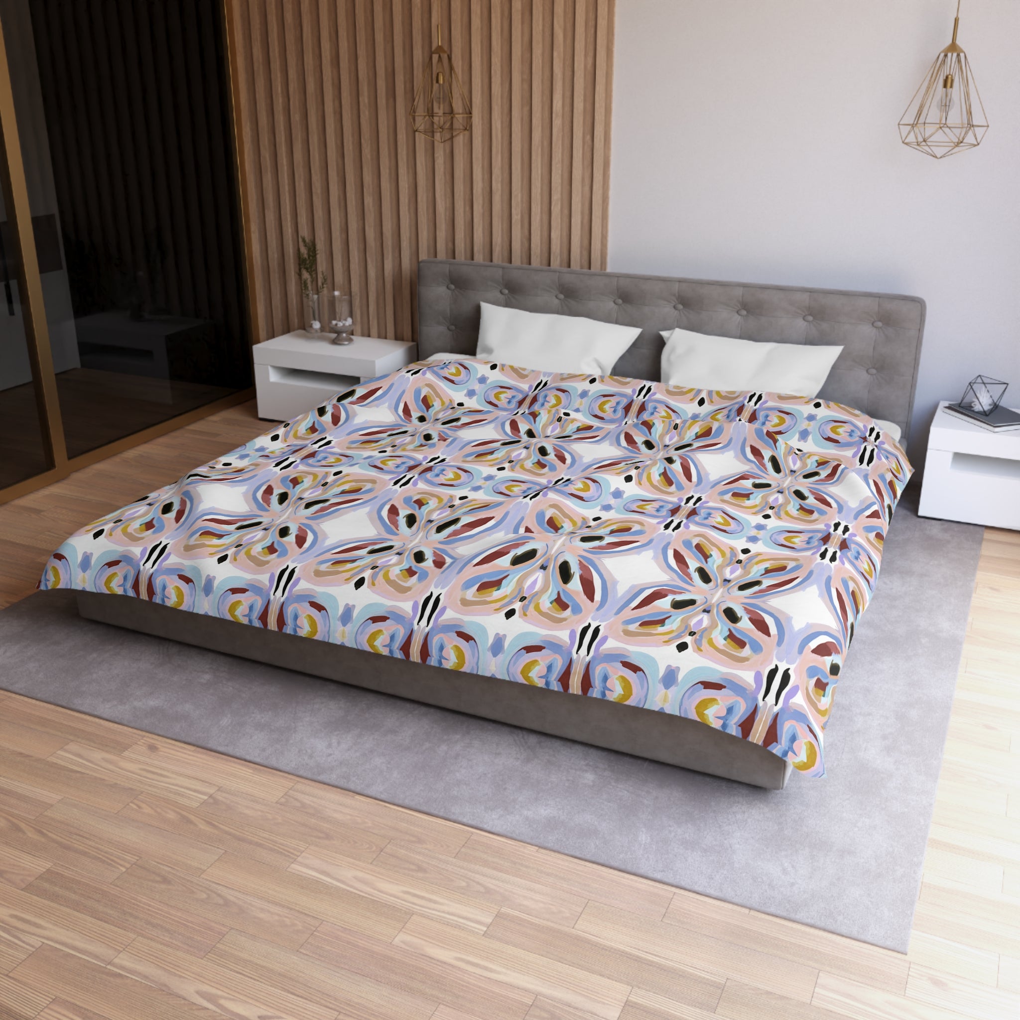 a modern bedroom with a large bed, a gray headboard, and a colorful patterned comforter. The room has a wooden floor and white walls, creating a clean and minimalist aesthetic.