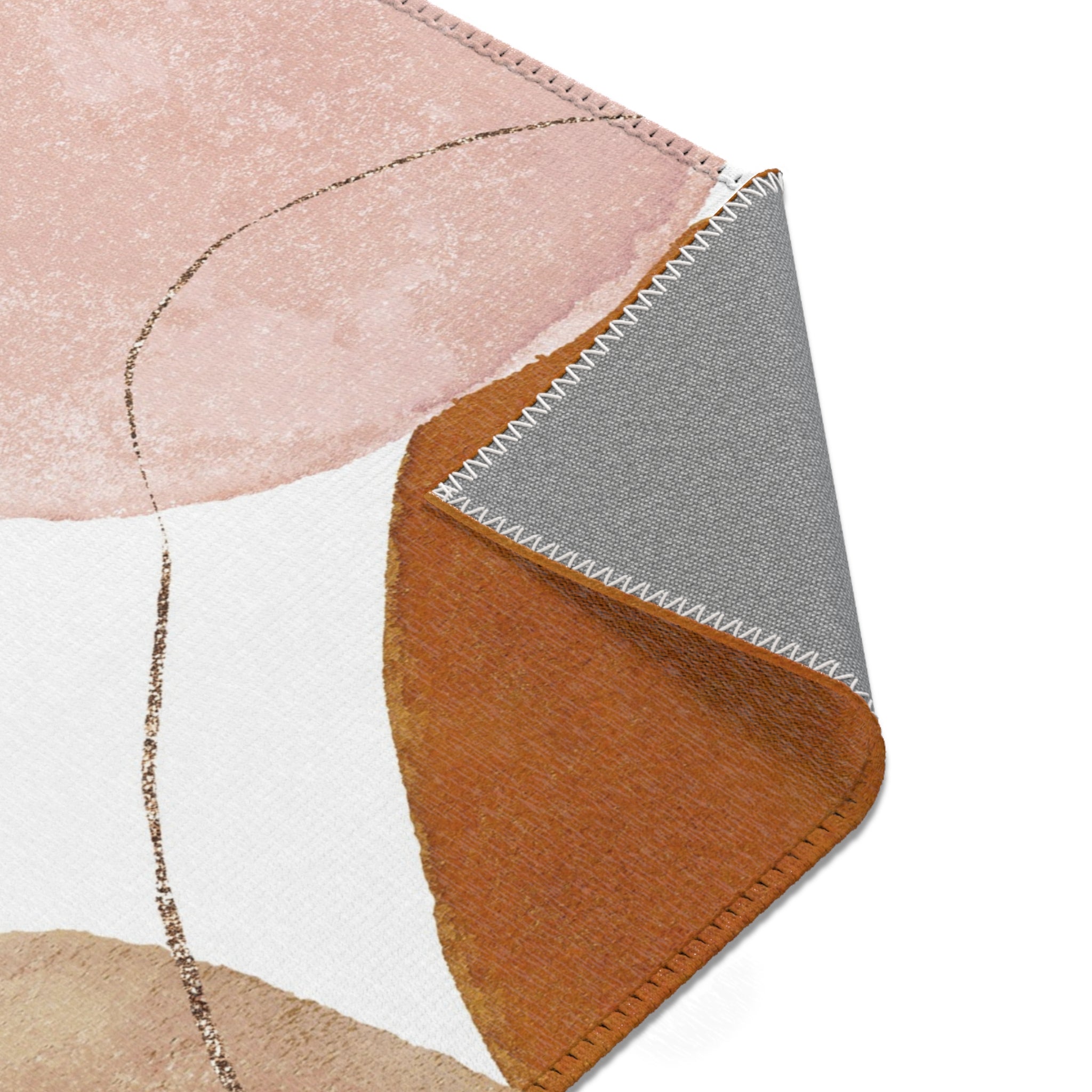 Modern rust, beige and blush pink abstract area rug shown under furniture in a styled room