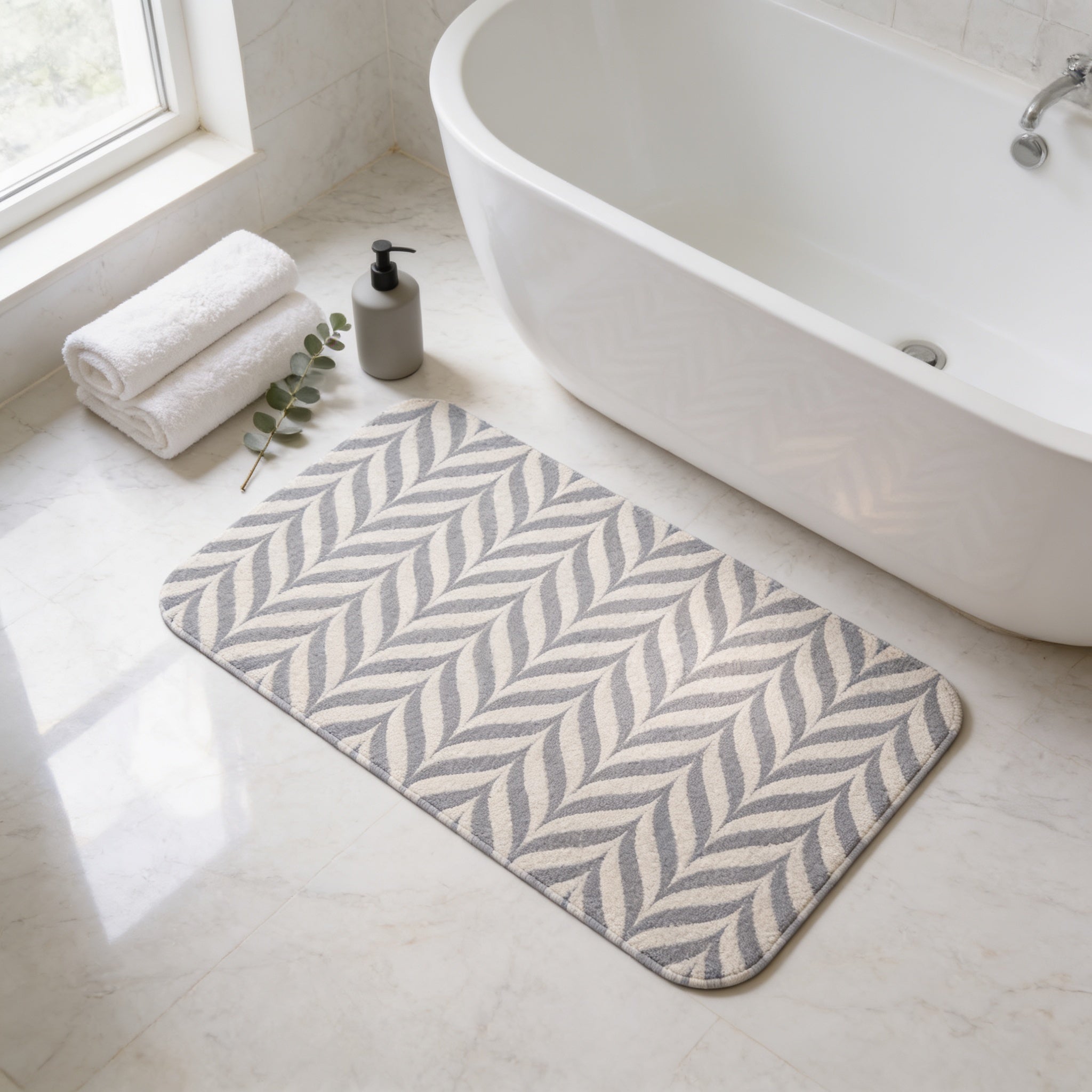a bathroom with a white bathtub, a decorative rug with a zigzag pattern, and rolled towels on the floor.