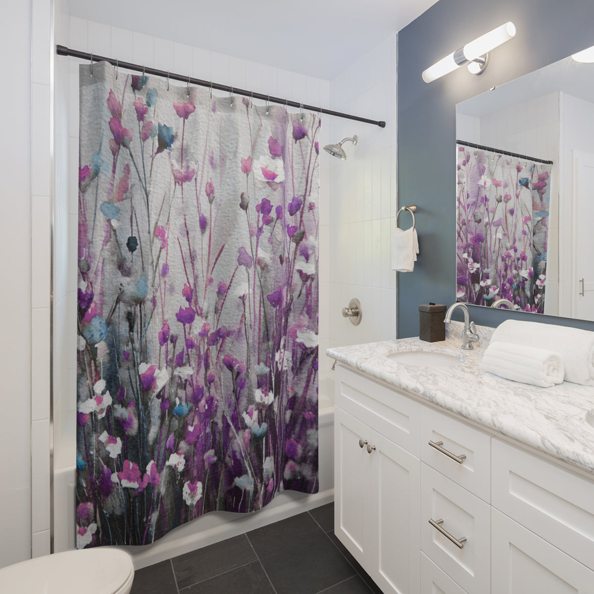 A modern bathroom with a white vanity, a shower curtain featuring a floral pattern in shades of purple and pink, and a mirror above the vanity.