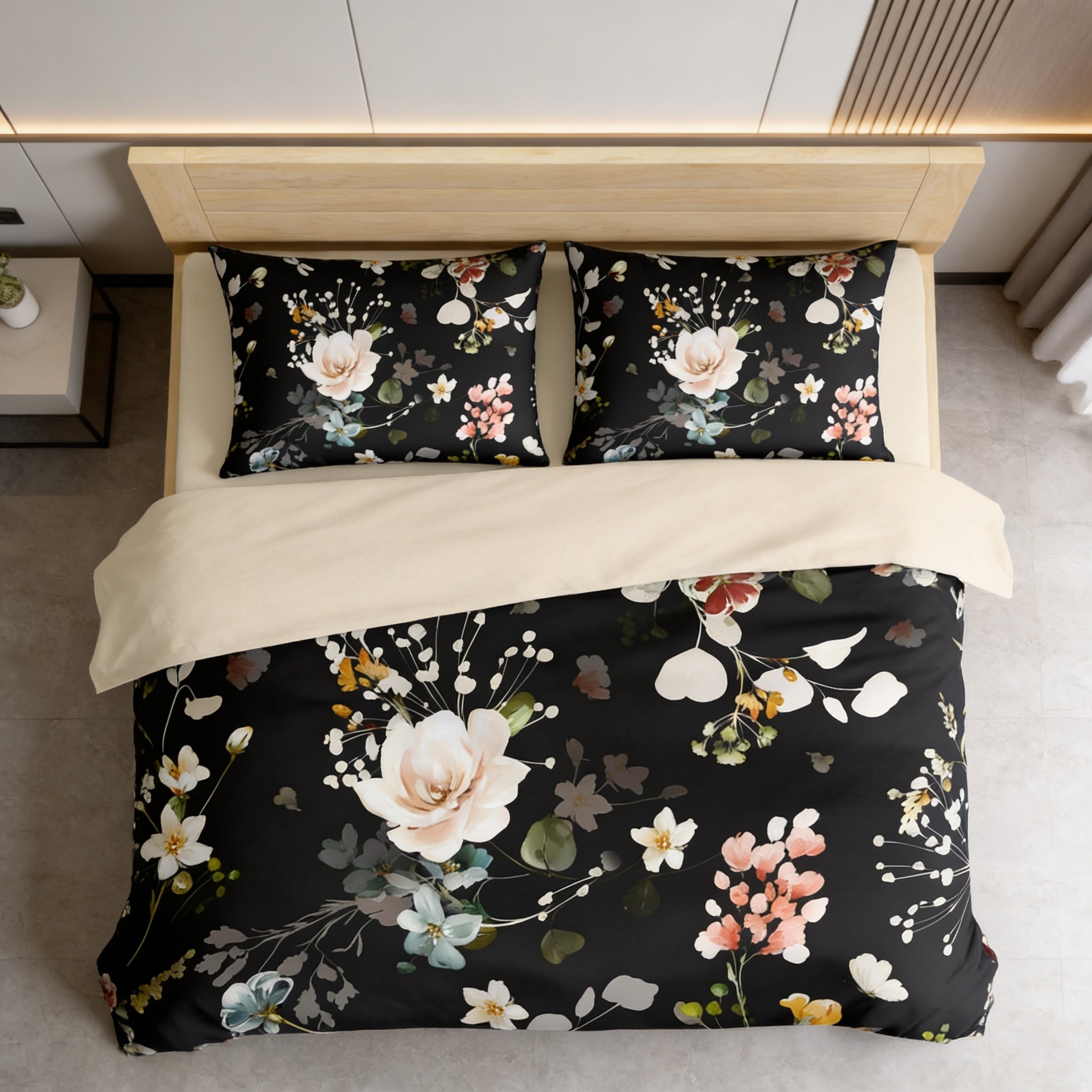 a bed with a black and white floral comforter and matching pillows, set against a white wall.