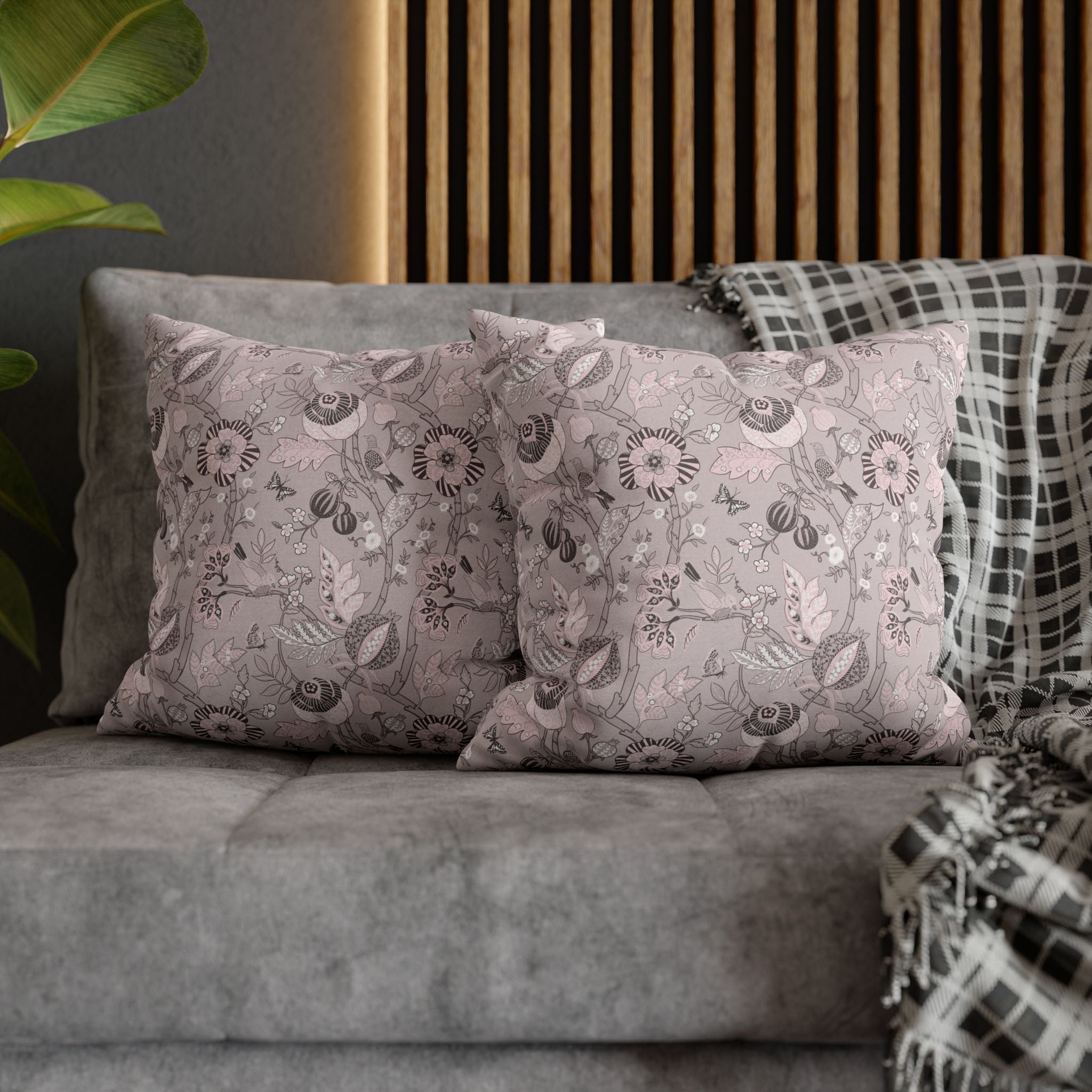 a gray sofa with two decorative pillows featuring a floral pattern in shades of pink and white. The pillows are placed on the sofa, creating a cozy and inviting atmosphere.