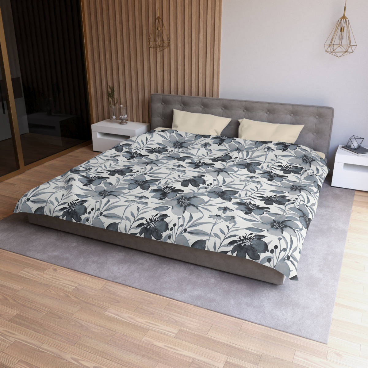 a modern bedroom with a large bed, a gray headboard, and a gray and white floral comforter. The room has a wooden floor and white walls, creating a serene and elegant atmosphere.