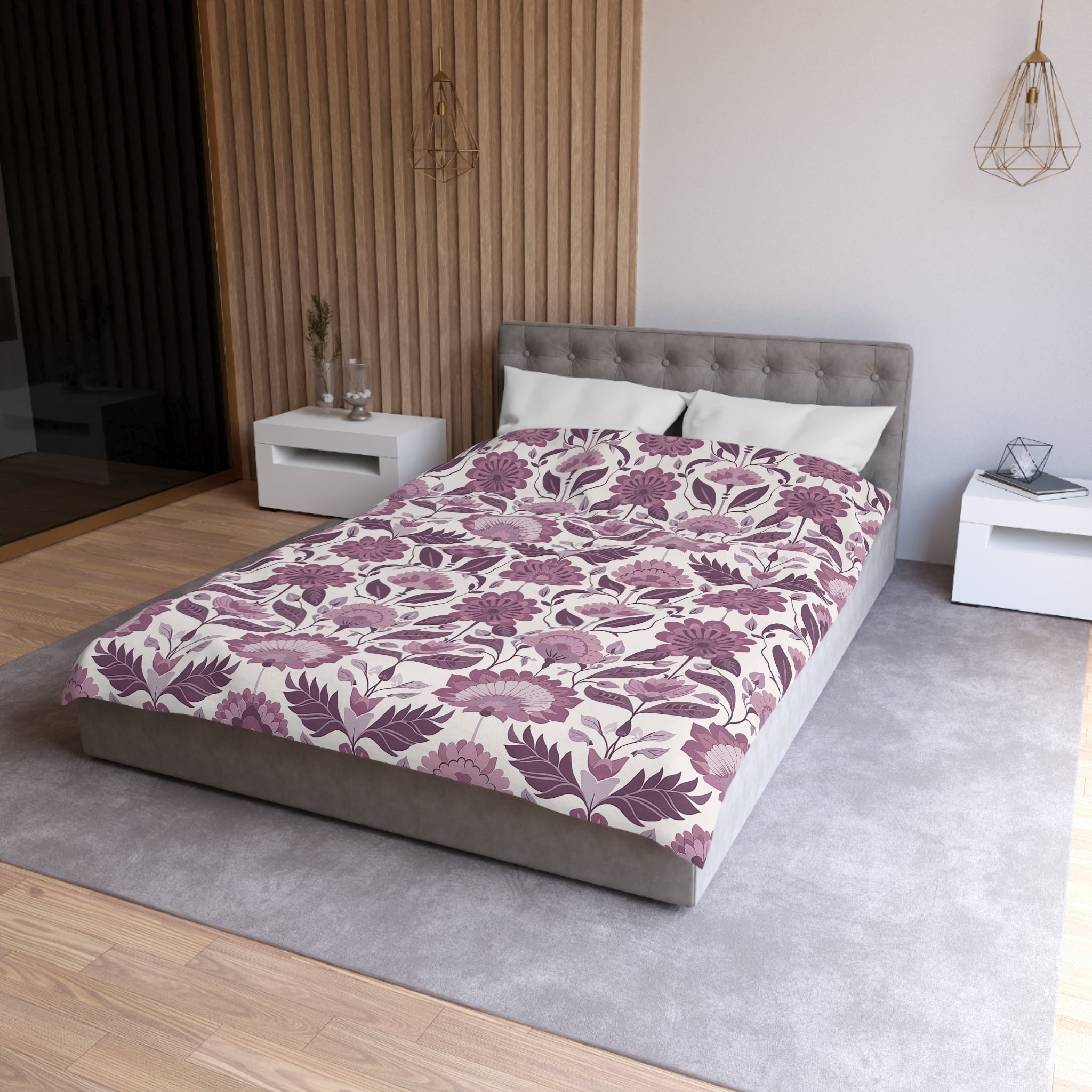a modern bedroom with a large bed, a gray headboard, and a floral patterned comforter. The room has a neutral color scheme with white walls and a gray carpet. There are two nightstands on either side of the bed, and a pendant light hangs above the bed.