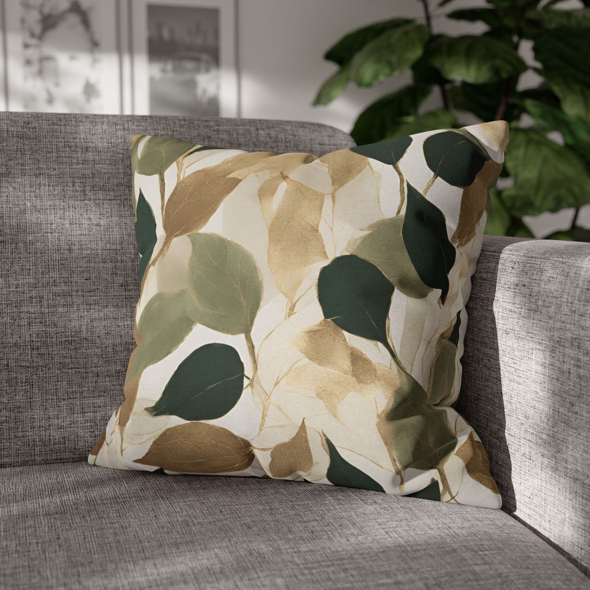A gray sofa with a decorative throw pillow featuring a leaf pattern in shades of green and brown.