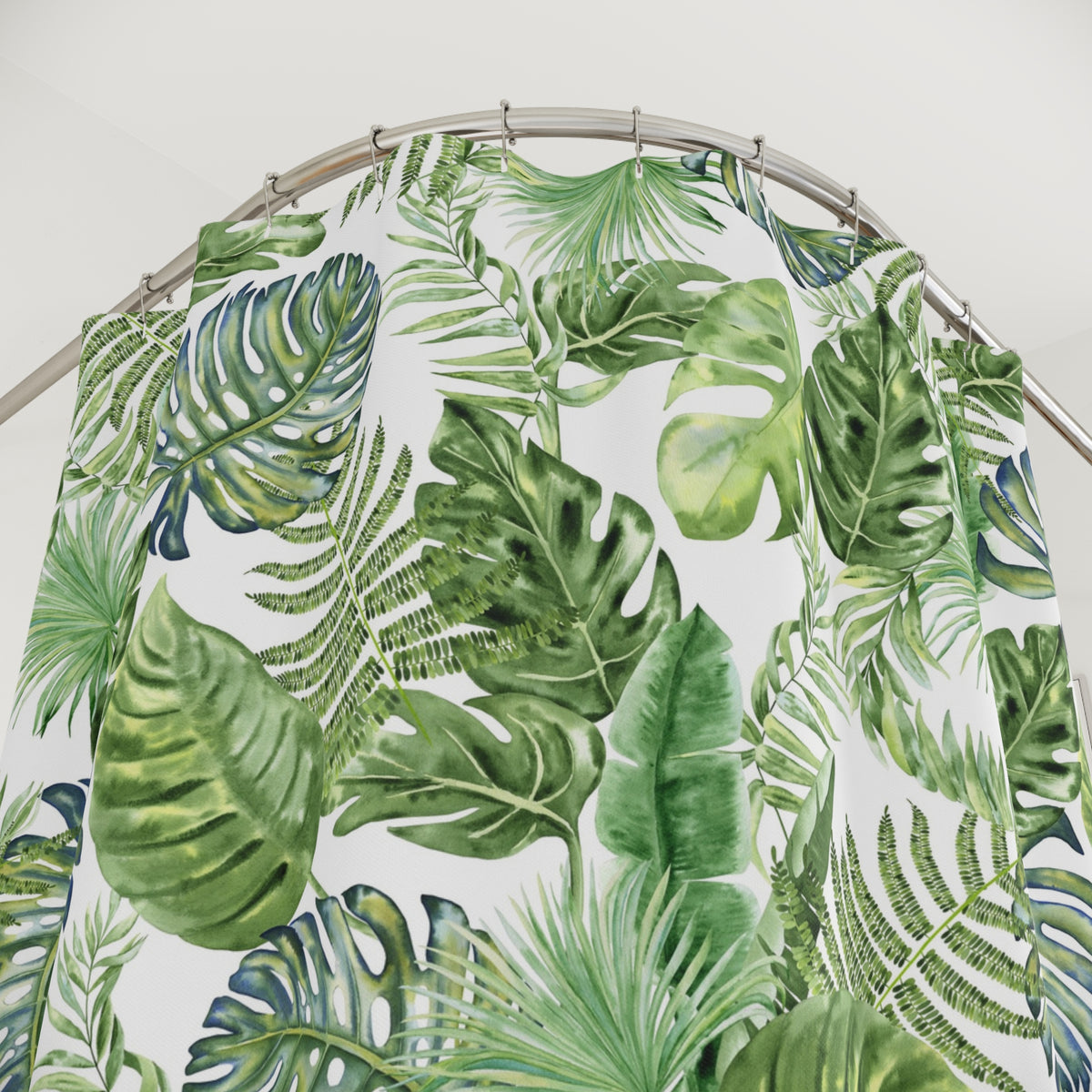 a shower curtain with a tropical leaf pattern, including palm leaves and ferns, hanging from a metal rod.