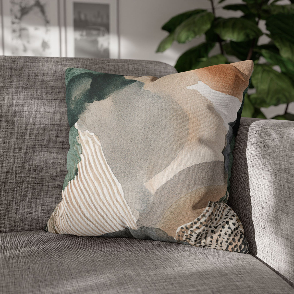 A gray couch with a decorative throw pillow featuring an abstract watercolor-style design in shades of green, gray, and beige.