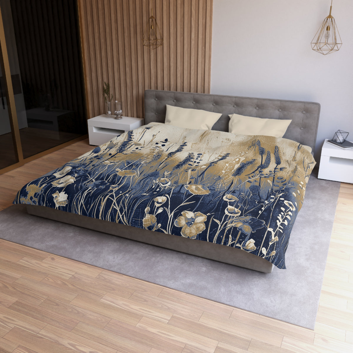 a modern bedroom with a large bed featuring a blue and gold floral comforter. The bed is positioned against a wall with a wooden panel. The room has a wooden floor and a white nightstand on the left side of the bed. There is also a pendant light hanging above the bed.
