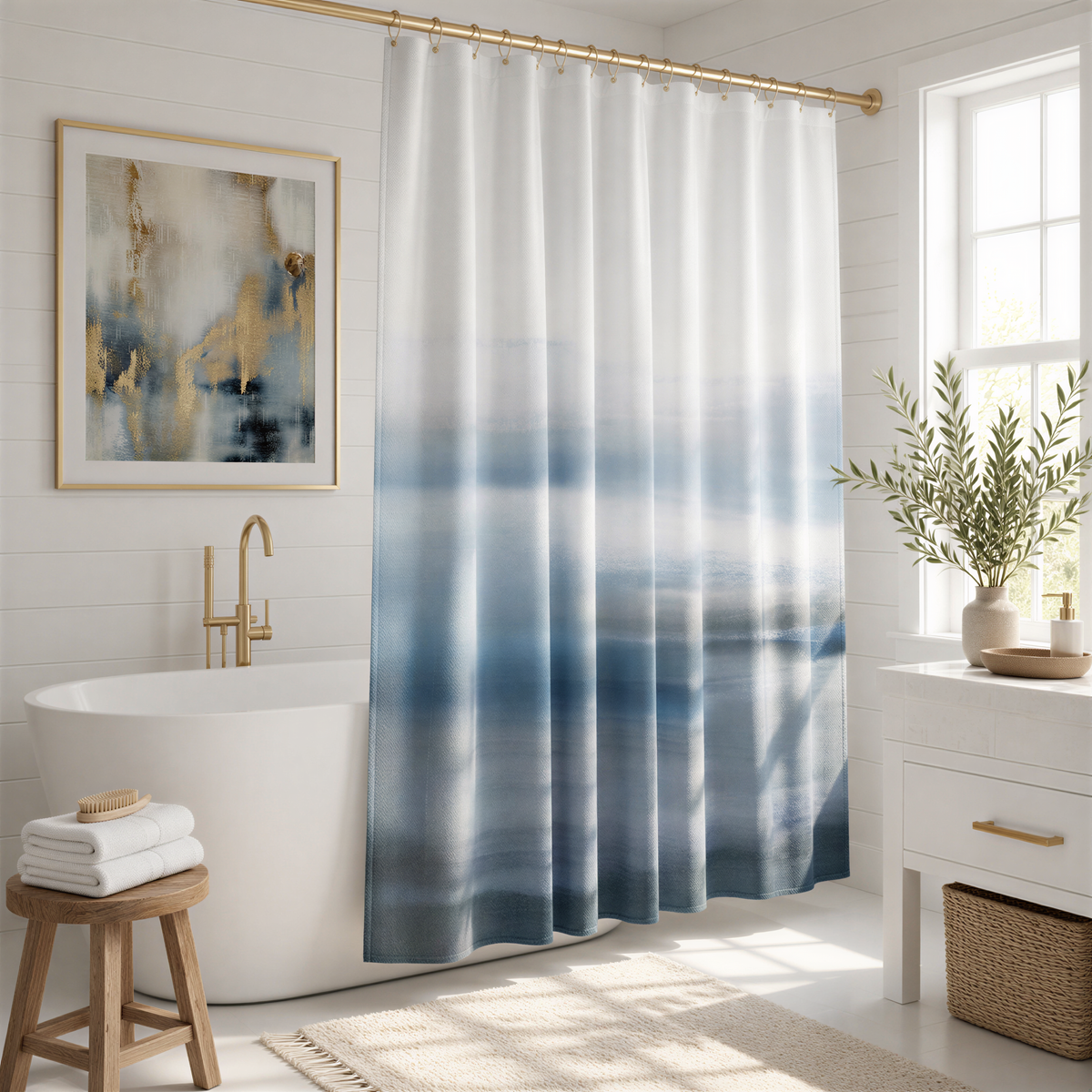 a modern bathroom with a white freestanding bathtub, a framed abstract painting on the wall, a shower curtain with a blue and white gradient, a wooden stool, and a potted plant.
