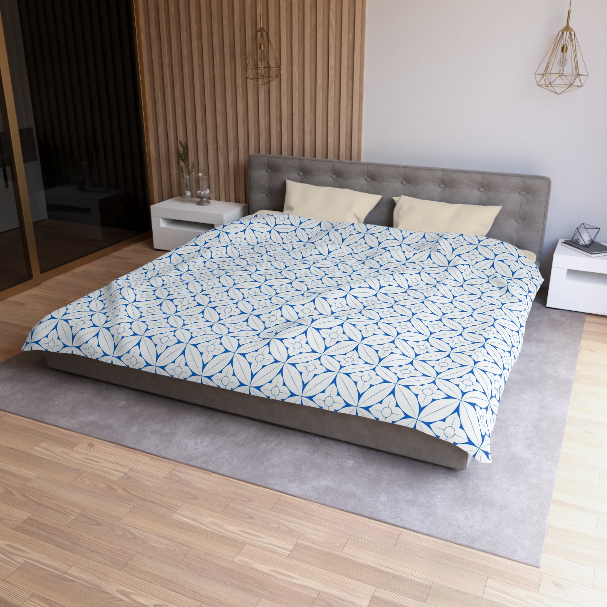a modern bedroom with a large bed, a gray headboard, and a patterned comforter. The room has a wooden floor and white walls, creating a clean and minimalist aesthetic.