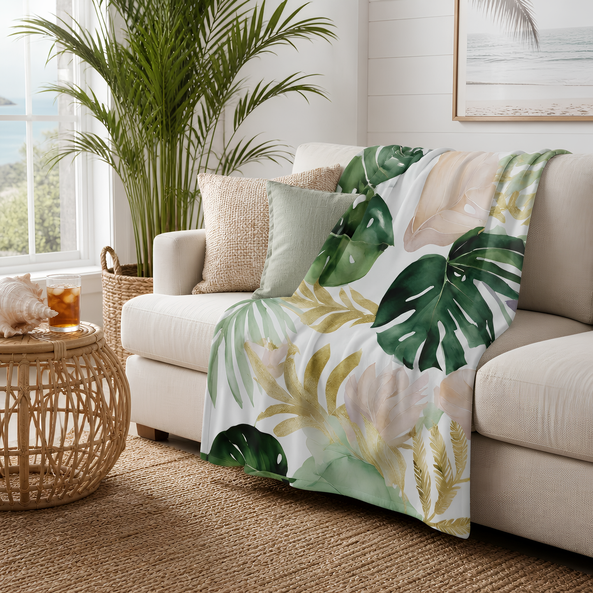 a cozy living room with a white sofa, a woven side table, and a large potted plant. The sofa is adorned with a throw blanket featuring a tropical leaf pattern in shades of green and yellow. The room has a warm and inviting atmosphere, with a window providing natural light and a view of the outdoors.