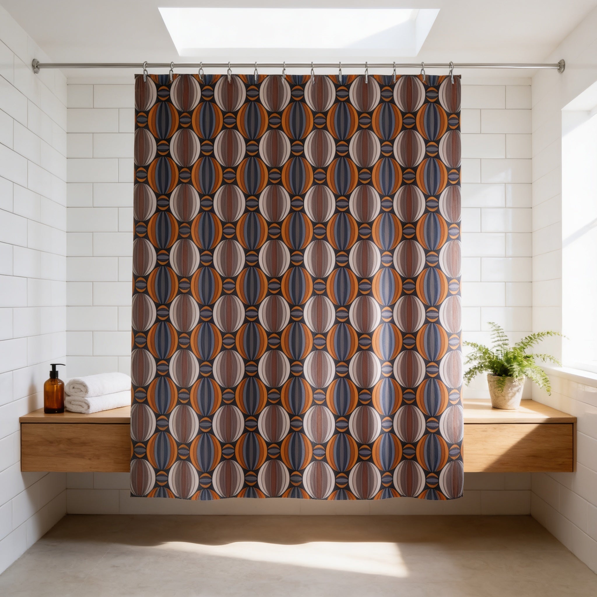 a bathroom with a shower curtain featuring a colorful, abstract pattern hanging from a rod. The shower curtain is placed above a wooden shelf, which holds a bottle and a potted plant. The bathroom has white tiled walls and a skylight, creating a bright and airy atmosphere.