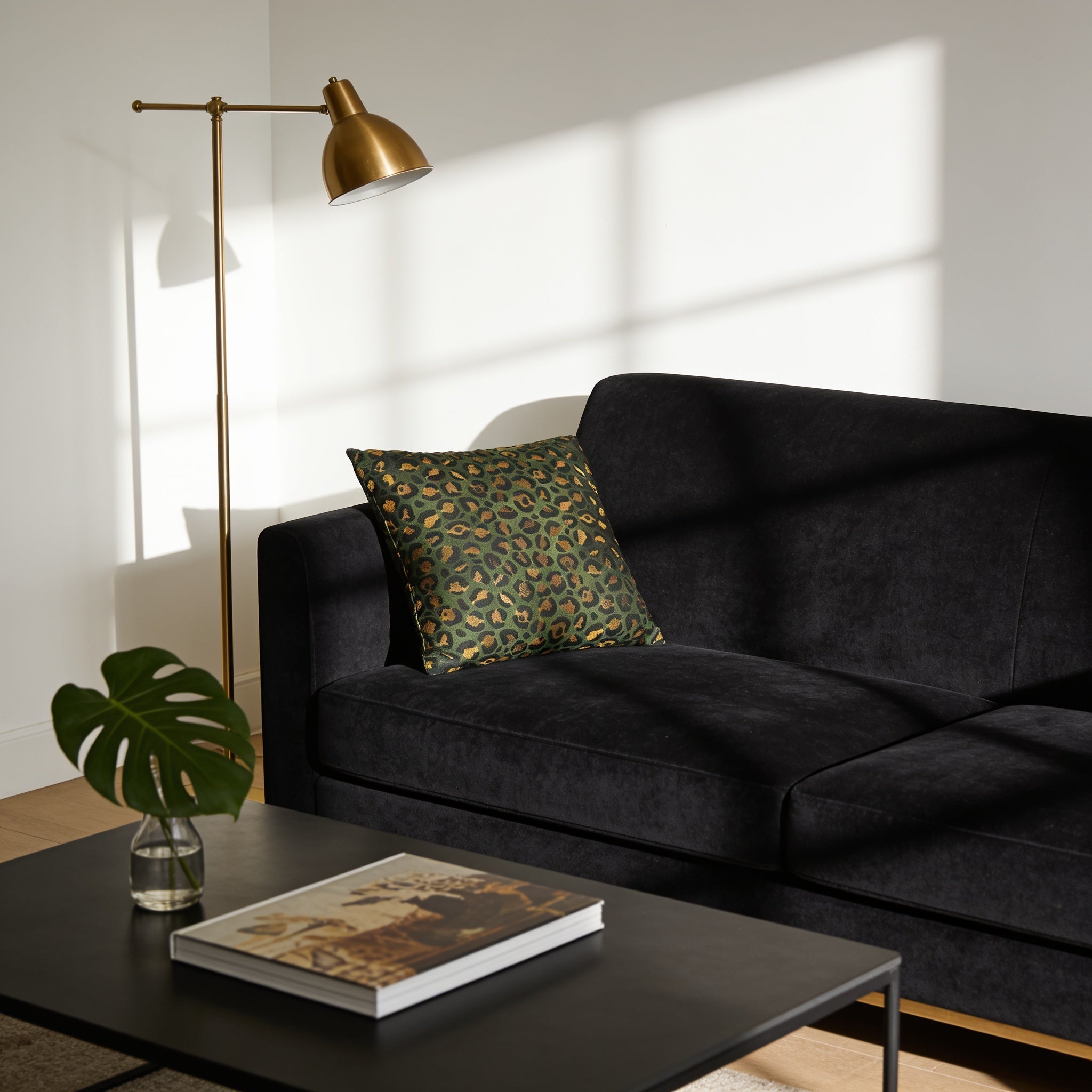 a modern living room with a black sofa, a black coffee table, and a gold floor lamp.